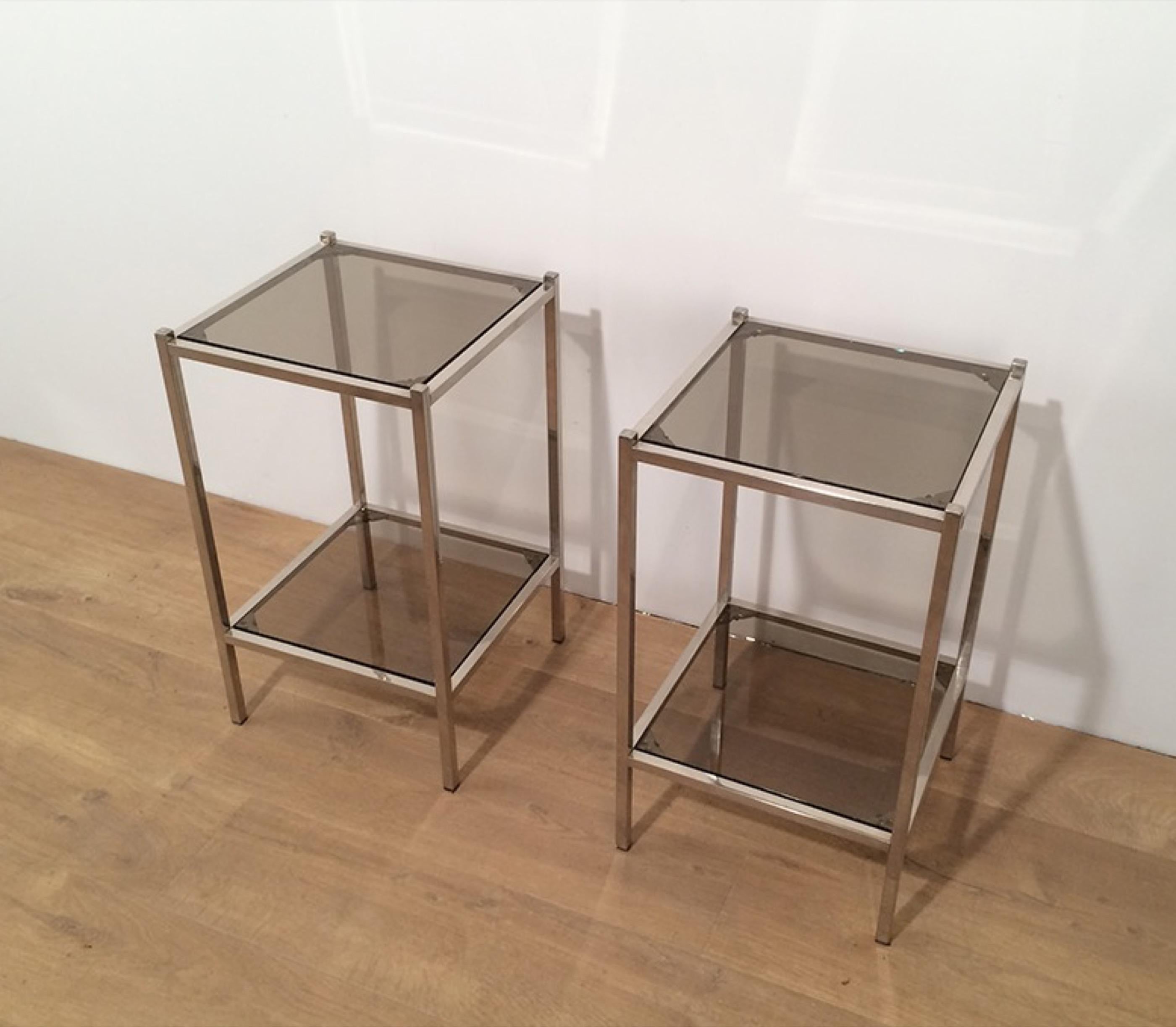 This pair of side tables is made of chrome with smoked glass shelves. This is a French work, circa 1970.