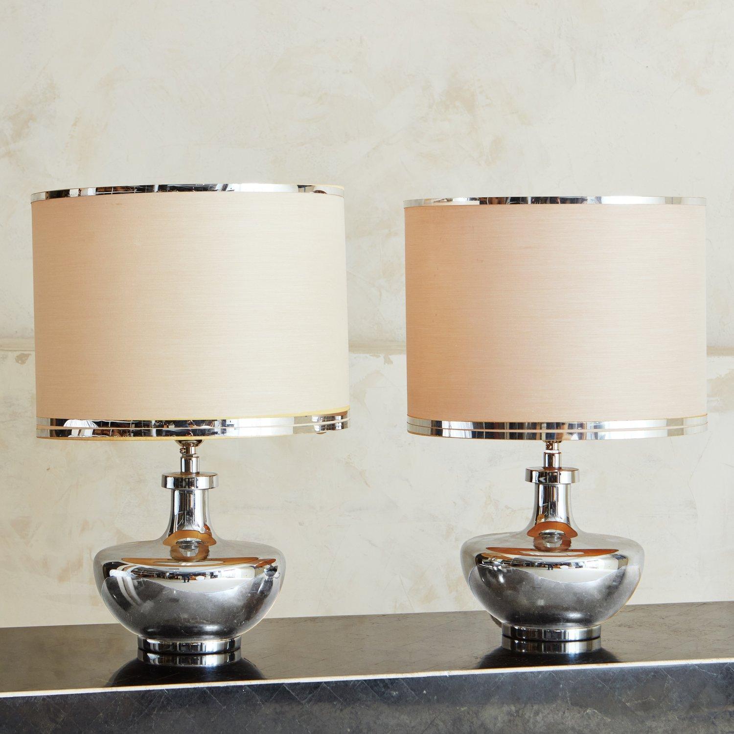 A gorgeous pair of table lamps designed by Estiluz for Maison Valenti in the 1970s. These lamps feature elegant, curved chrome bases and original shades with chrome details. Retains original label ‘E Exclusivos Valenti’ tag. 

Estiluz is an iconic