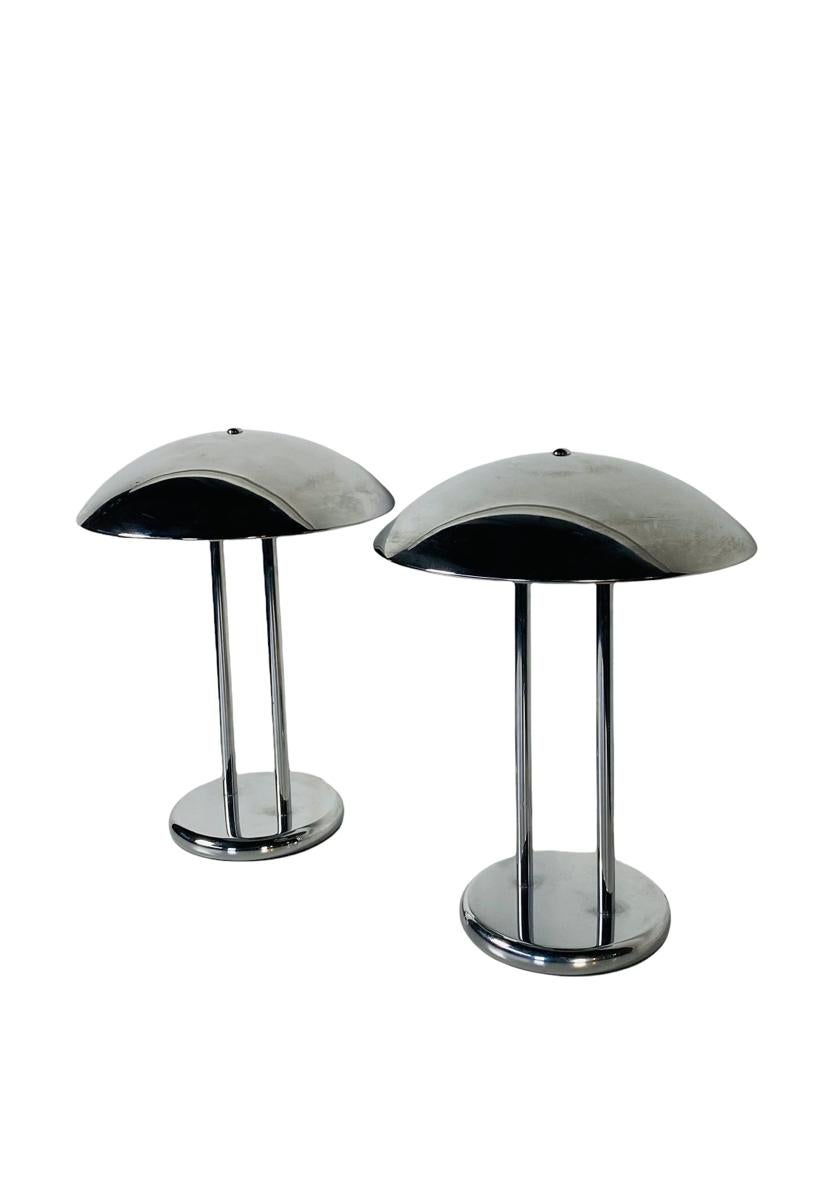 Pair of Chrome table lamps with half dome shade. These lamps feature two tubes connecting the round base to the half-dome, fixed shade. Each lamp allows for two standard sized bulbs. Perfect for end tables or night stands. The lamp operates with a