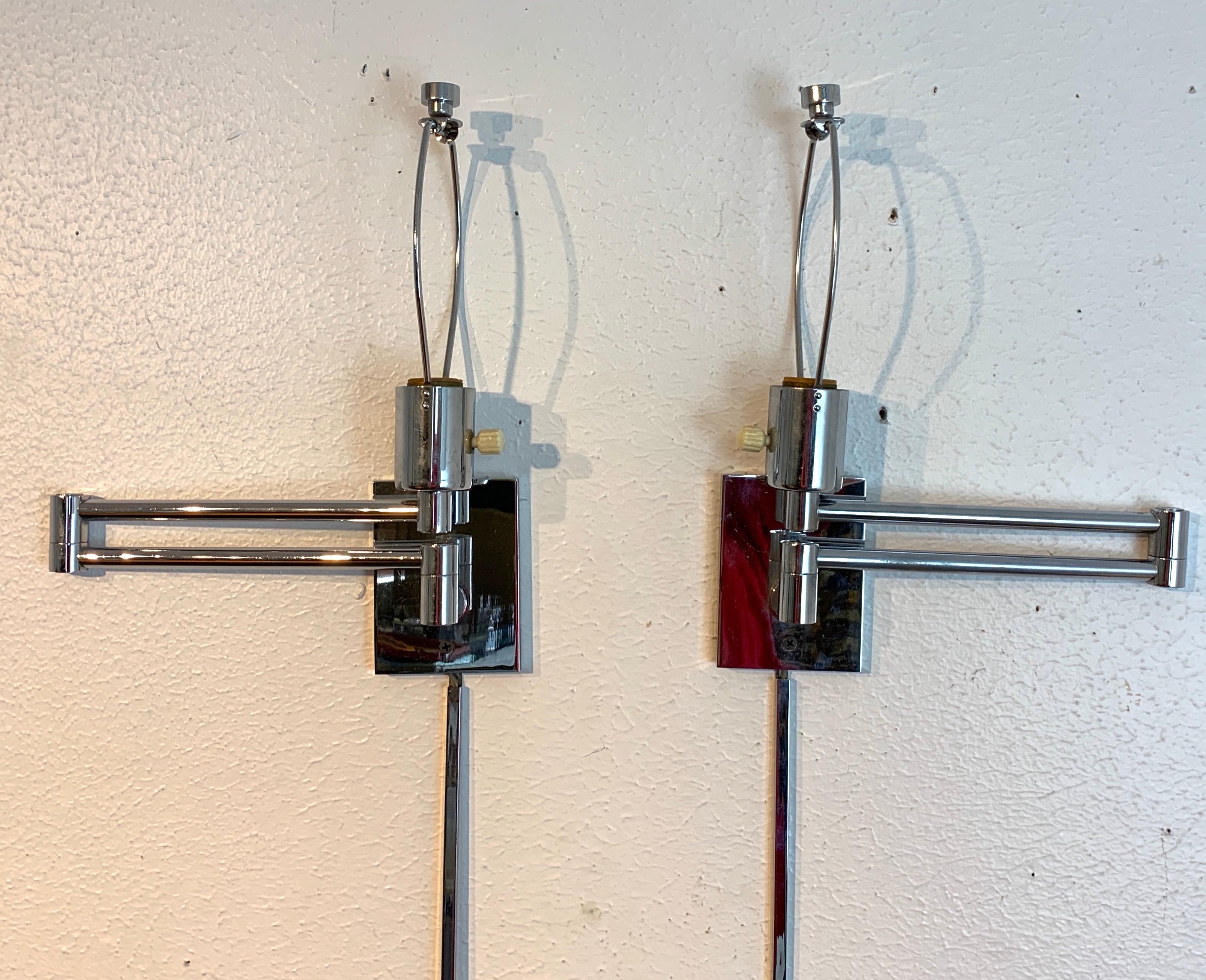 Pair of chrome wall-mounted swing arm lamps designed by George W. Hansen, in 1947 Chrome wall mount plate, and has the original finials. Uses a standard bulb up to 100W. Includes the 36