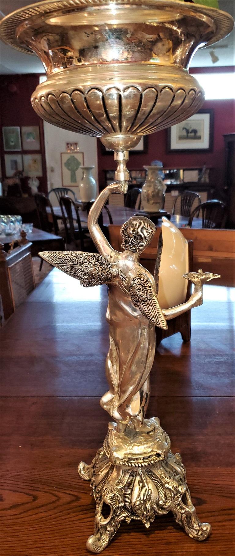 Presenting a lovely pair of chromed angel centrepieces.

Featuring a pair of female angels with wings and holding a bird in their right hand. Standing on ornate pedestals on 4 feet and holding aloft a centerpiece bowl/urn in their left hand. Each
