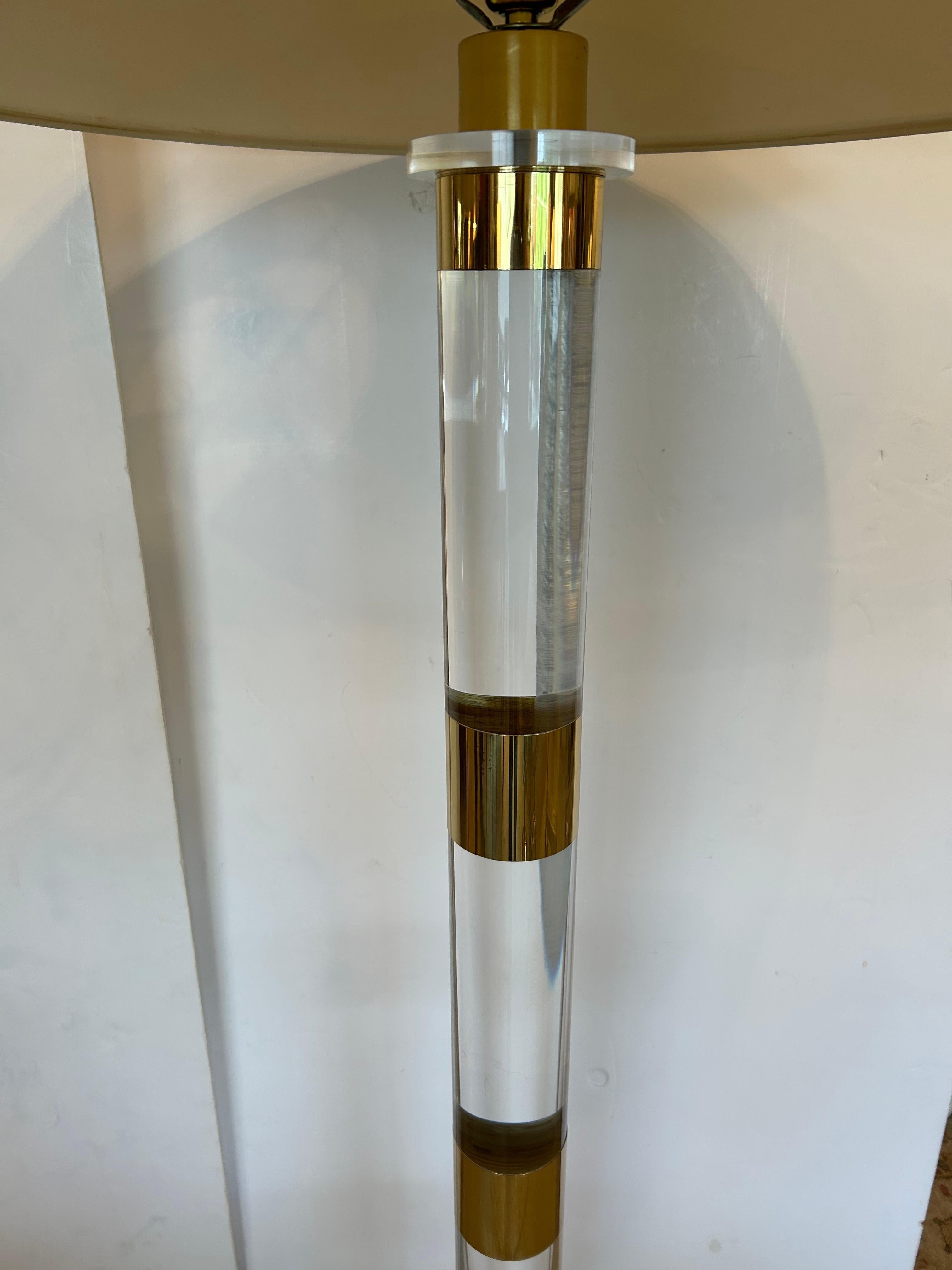 Elegante par de lámparas de pie modernas de mediados de siglo con columnas de lucita de 10 cm de diámetro y anillos de latón espaciados uniformemente arriba y abajo de las columnas.