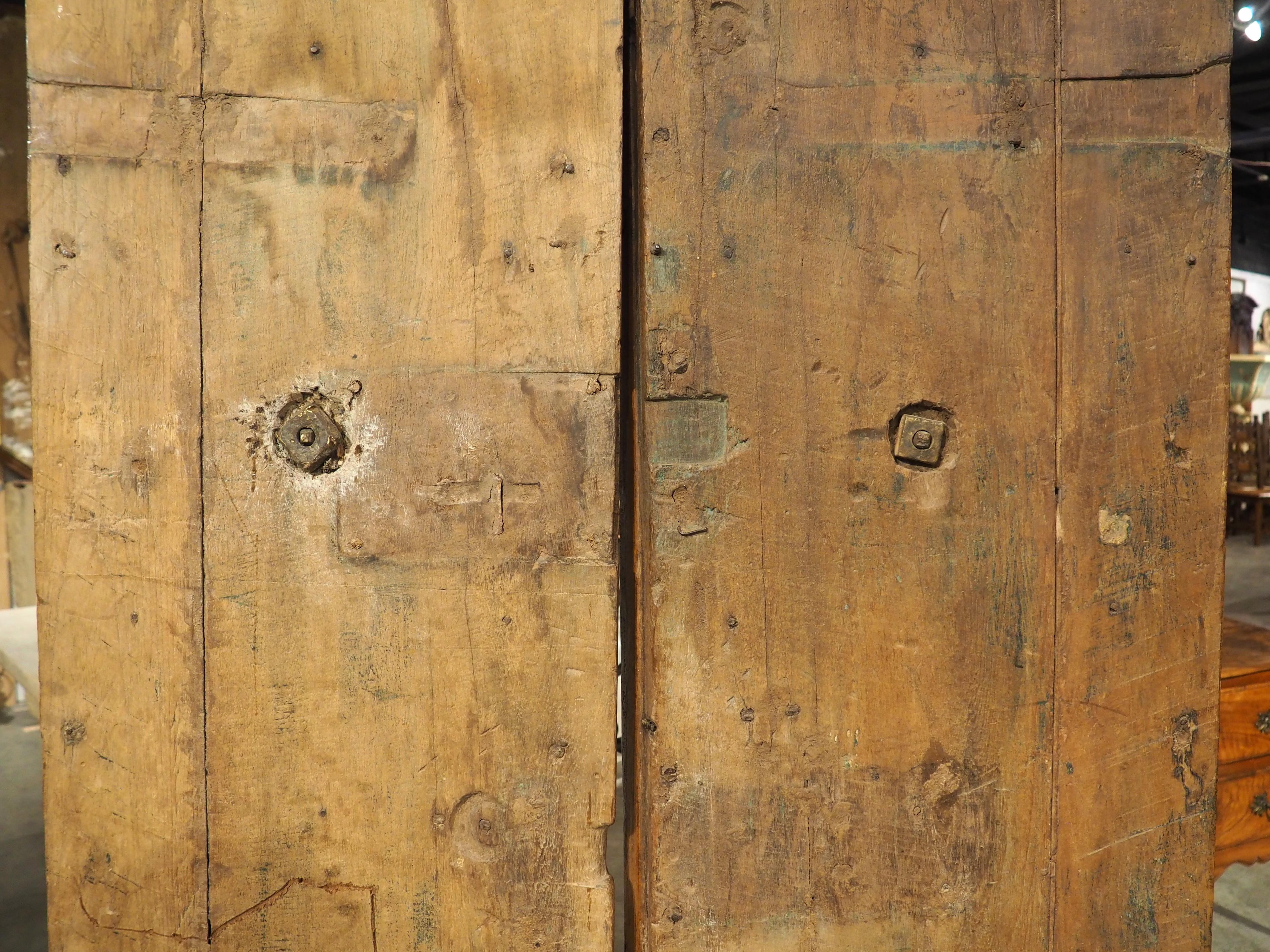 Spanish furniture and architecturals of the 18th century, such as this pair of walnut wood entry doors, were highly influenced by French stylings. Hand-carved circa 1750, the doors feature deep, sinuous moldings, reminiscent of the curvaceous motifs