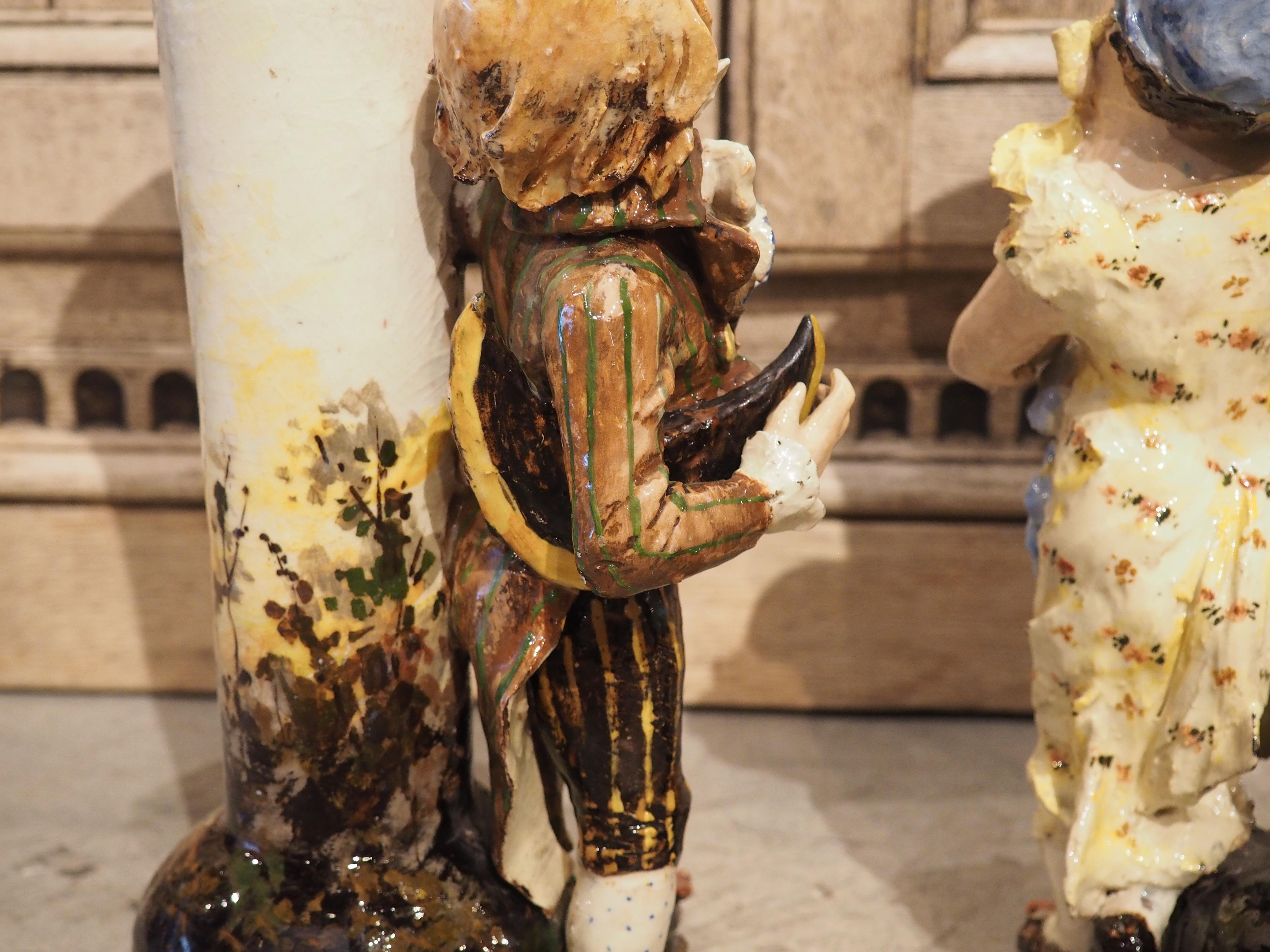 Cette merveilleuse paire de vases figuratifs barbotine a été sculptée et peinte à la main en France, vers 1890. Les corps principaux des vases représentent un arbre en fleurs sur un fond blanc et bleu représentant le ciel. Les deux pieds ont été