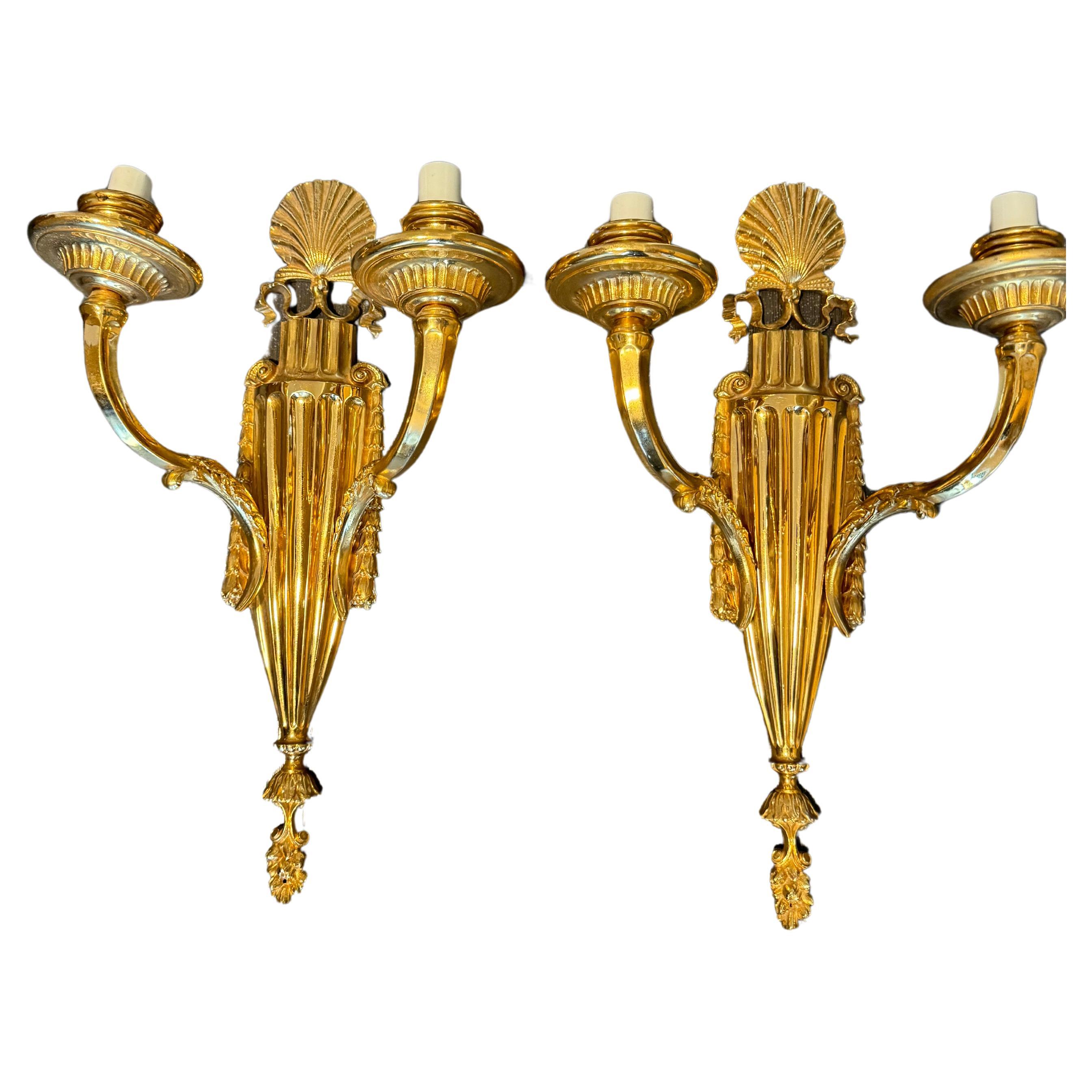 A pair of circa 1900’s Caldwell double light sconces with shell design stop.