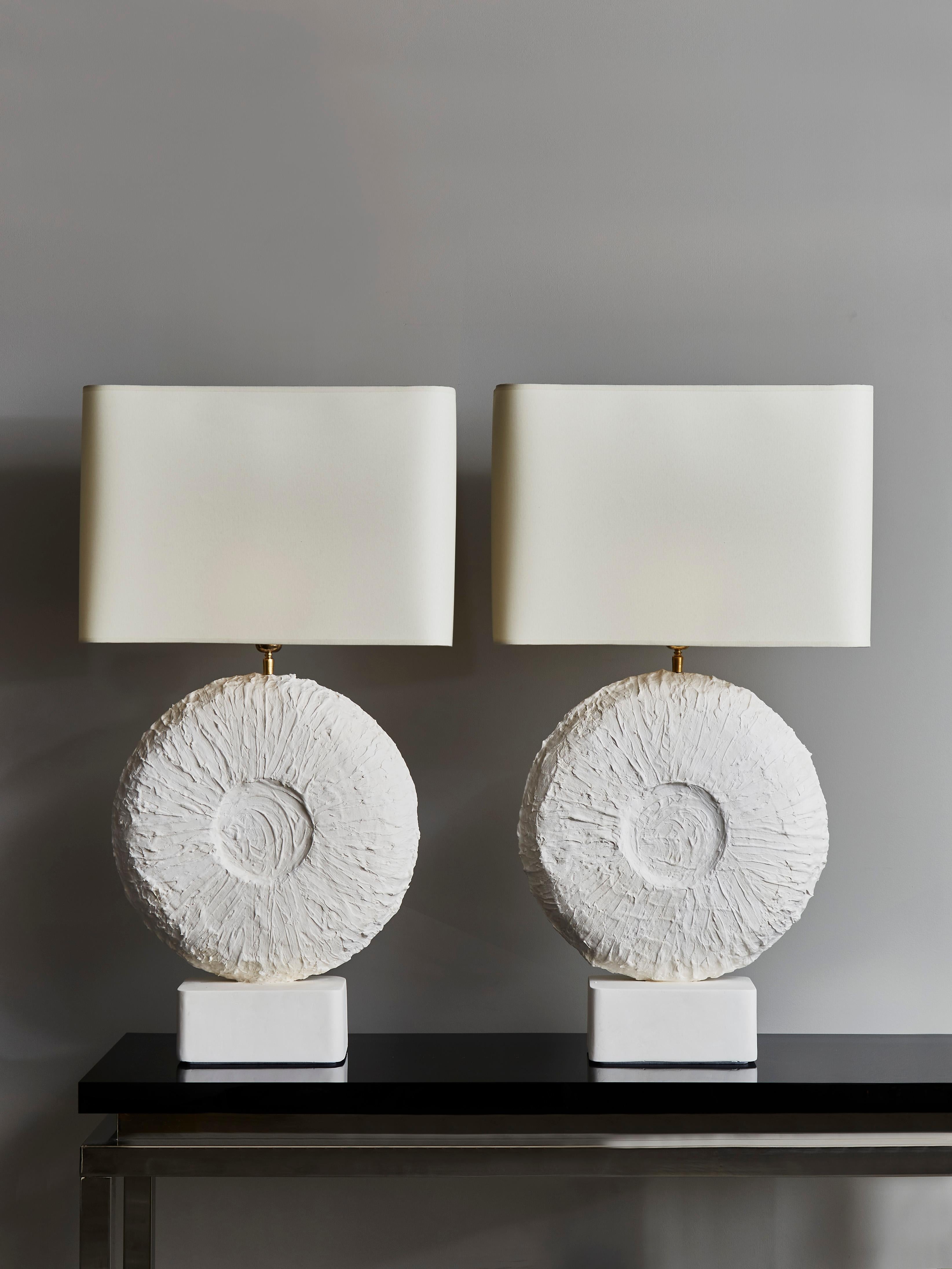 Pair of beautiful table lamps made of a round textured plaster centerpiece and feet with brass settings.

Contemporary work made in France.
     