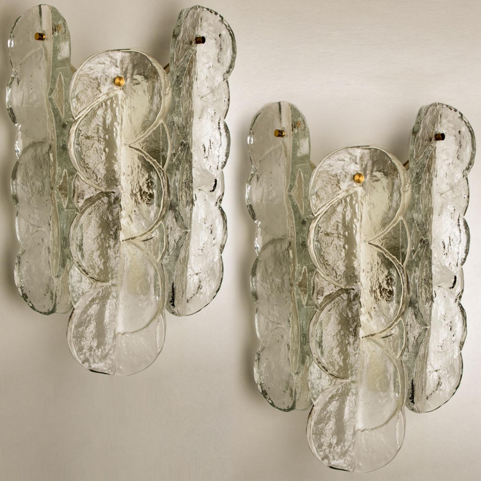 Coppia di appliques Kalmar con vetro opalino chiaro e testurizzato. Il bellissimo e spesso vetro testurizzato è completato dalla ferramenta cromata. Design semplice e pulito. Soffiato a mano, realizzato in vetro trasparente. Apparecchi di alta