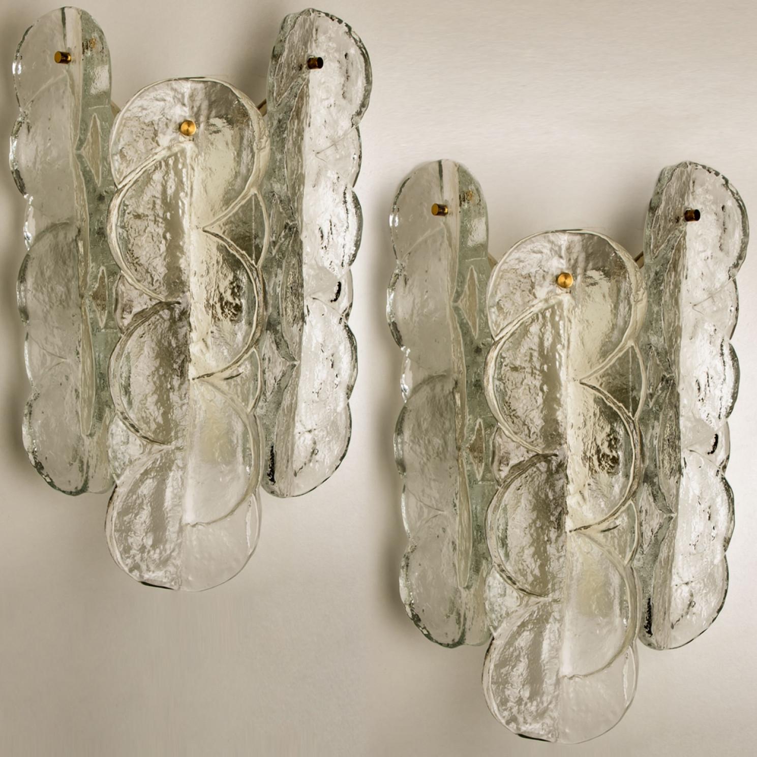 Pareja de apliques de pared Kalmar en forma de espiral con cristal opalino transparente texturado. El hermoso cristal de textura gruesa se complementa con los herrajes cromados. Diseño sencillo y limpio. Vidrio fundido soplado a mano, de vidrio