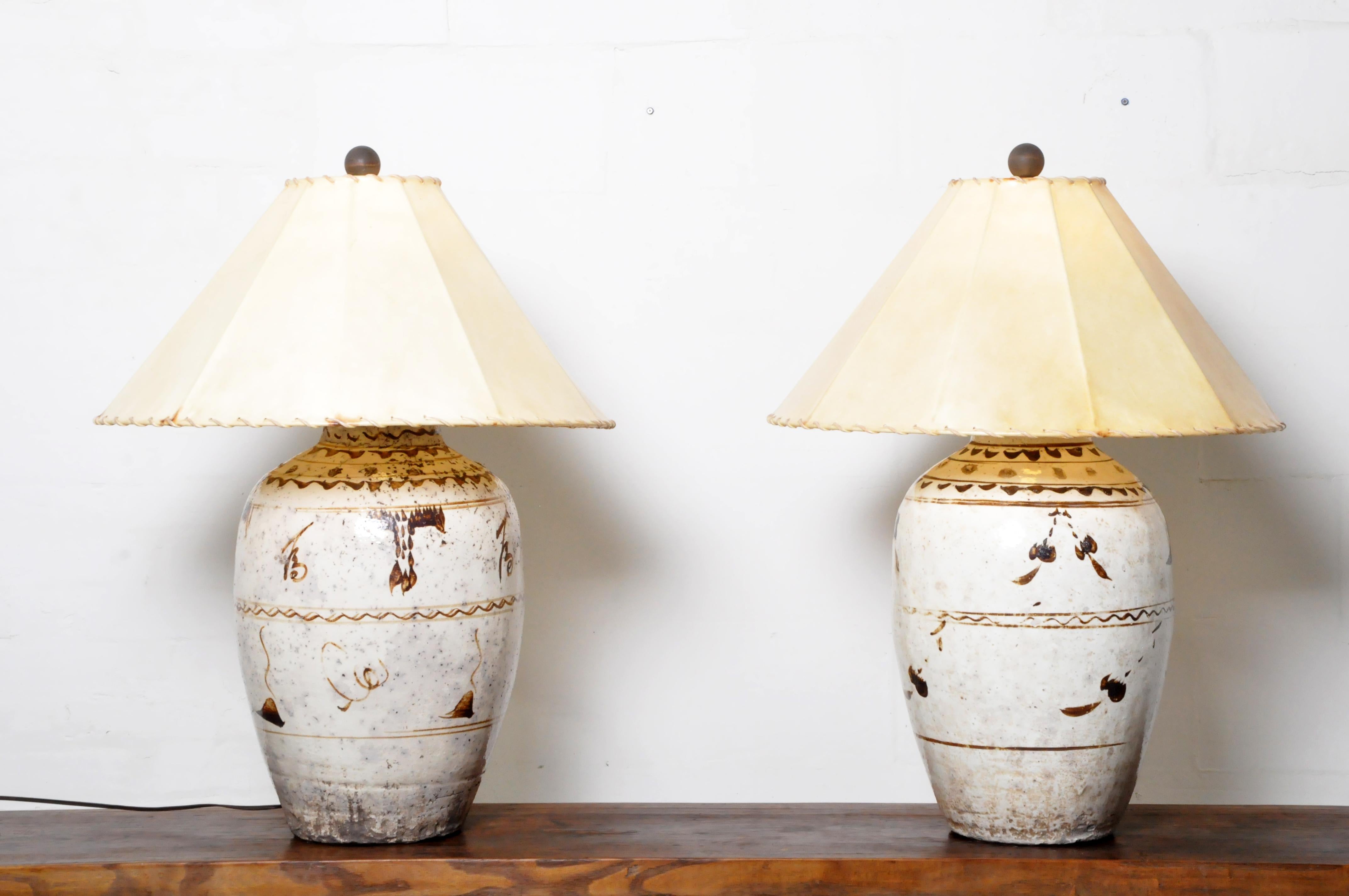 Large, solidly potted sixteenth-century Ming Period Cizhou pottery vases converted into lamps. The vases are decorated in the traditional manner with caramel glazes upon a cream ground. Once used to hold fortified Chinese wines and liquors. Wear