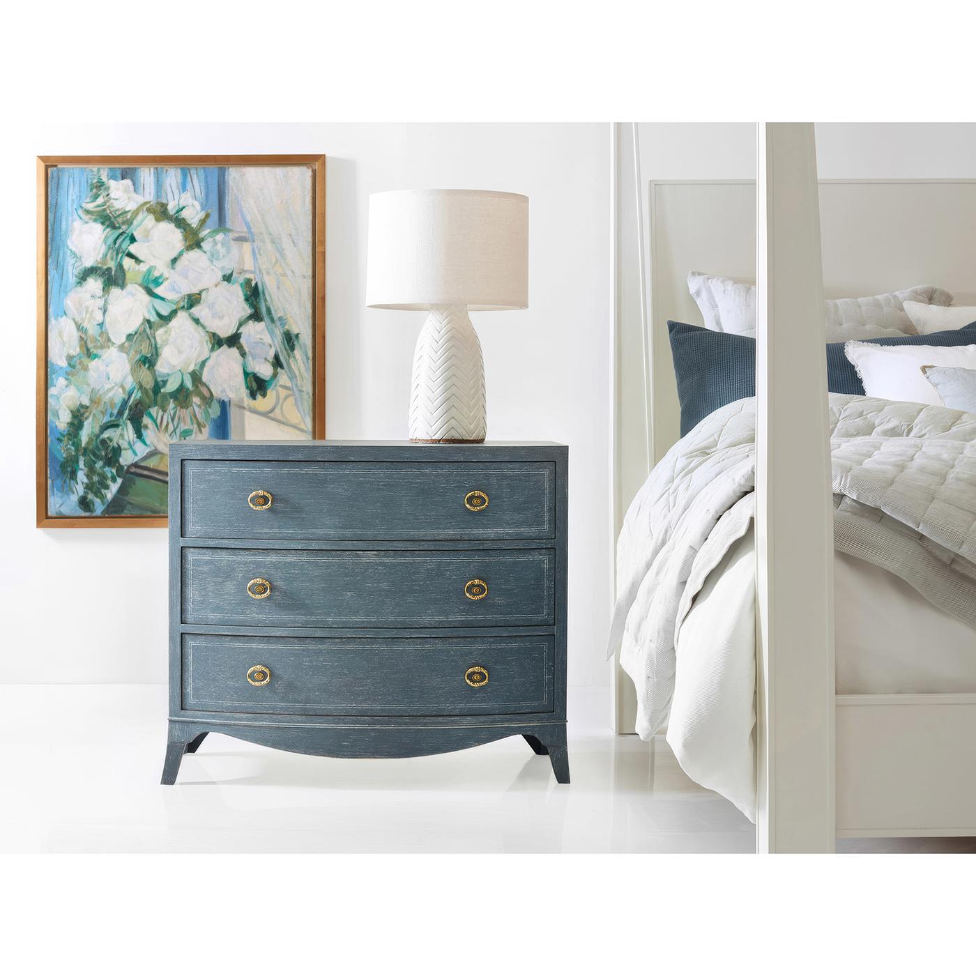 This nightstand embodies timeless elegance with its refined proportions and thoughtful details. The distressed blue painted finish creates an elegant, clean canvas that highlights its architectural elements, while a painted line inlay and decorative