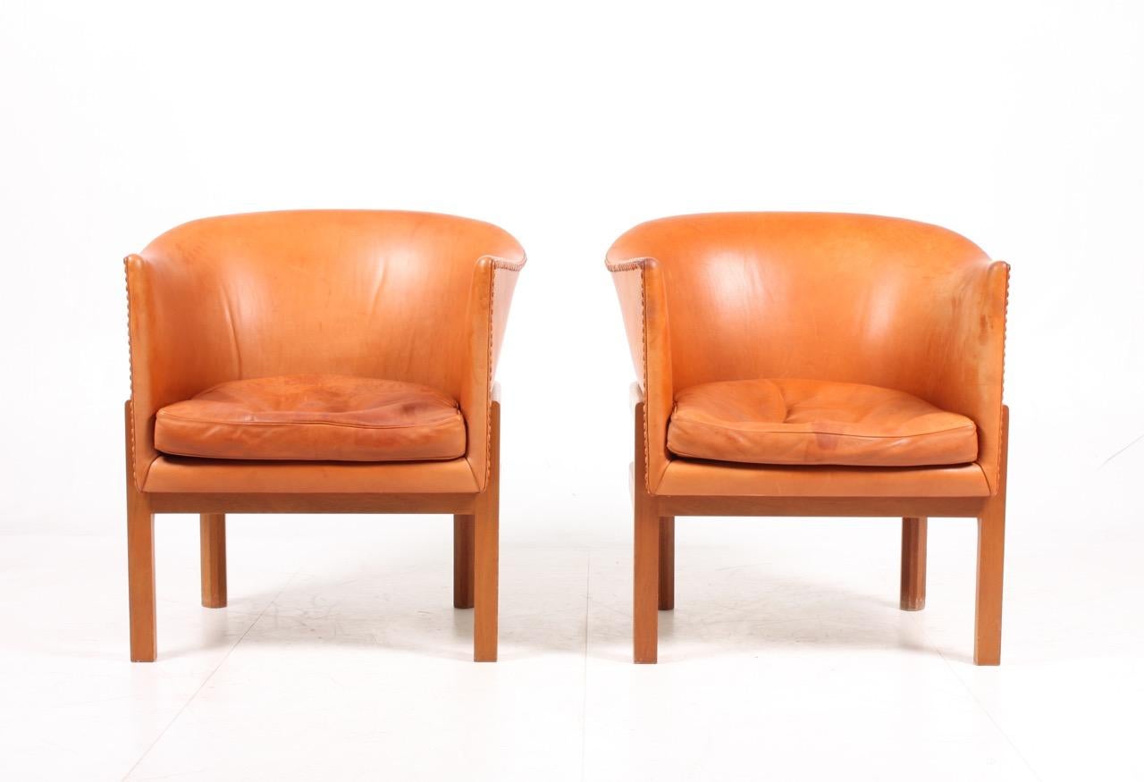 Pair of classic lounge chairs in solid mahogany and patinated leather. Designed by Maa. Mogens Koch for Rud Rasmussen cabinetmakers in 1936. Great original condition.