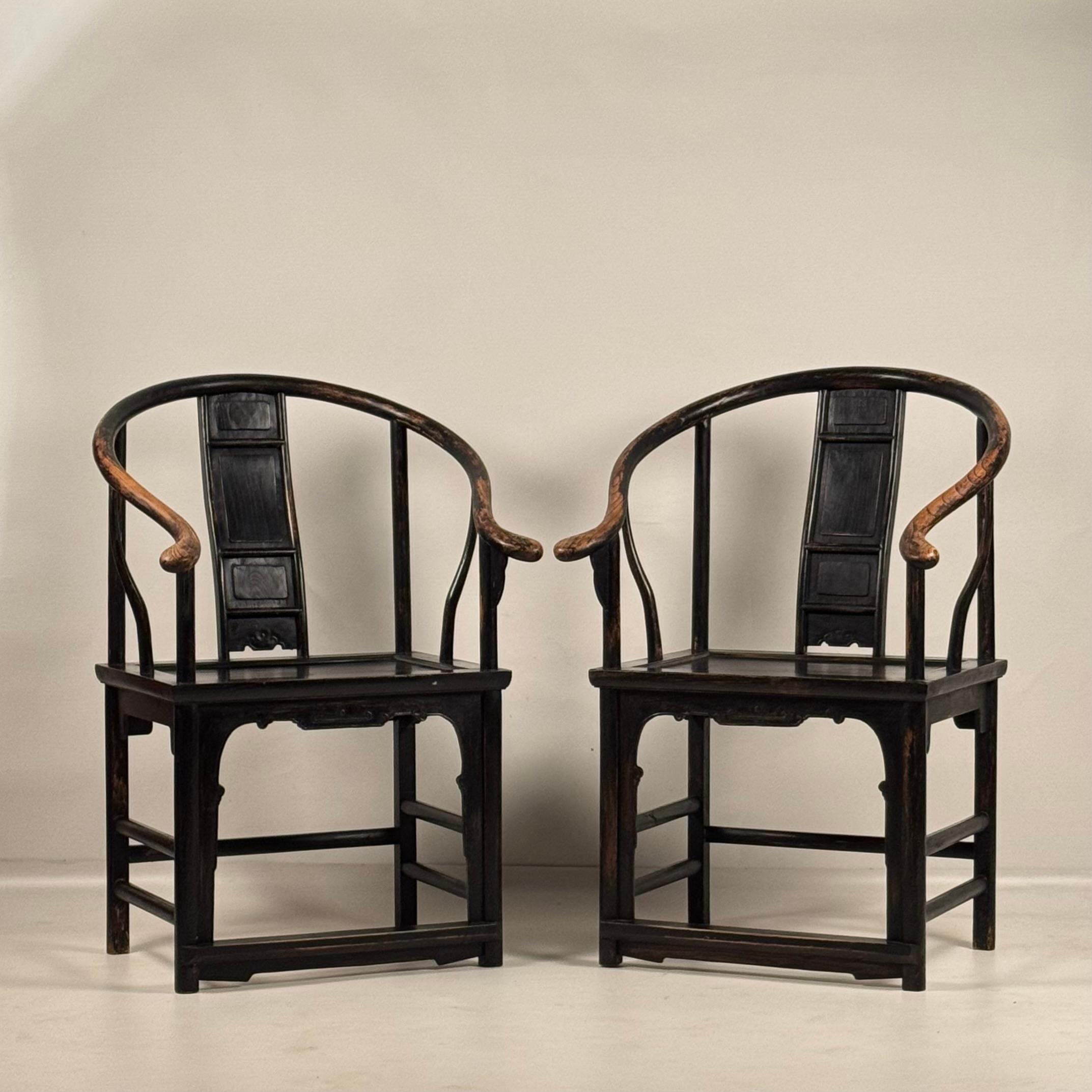 Cette paire de fauteuils chinois anciens en fer à cheval présente un dossier en S incurvé et des accoudoirs légèrement usés. 
