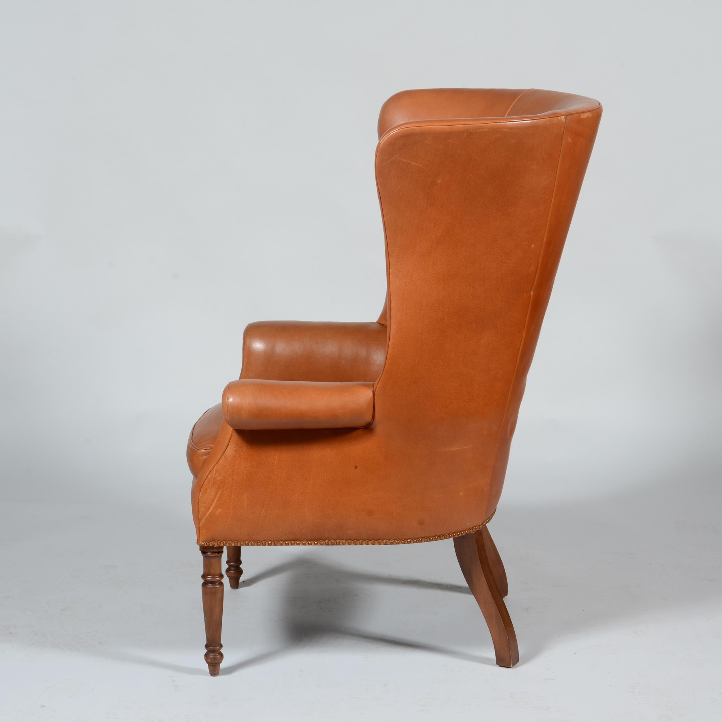 A classic pair of saddle leather high back wing back chairs that feature exaggerated proportions and a perfect amount of patina to the high quality leather. A look that would mix well with Modern and other classic looks.