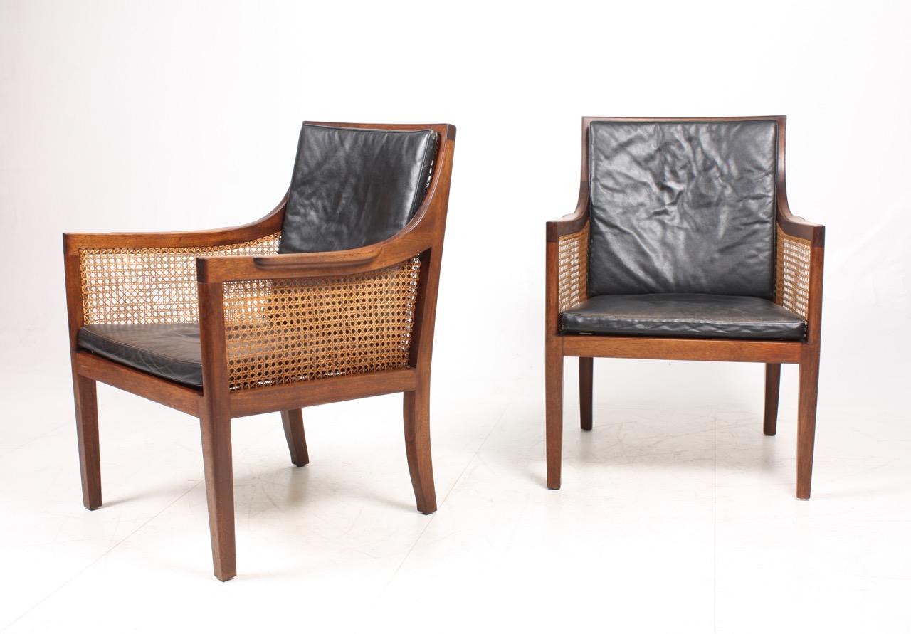 Pair of classic lounge chairs solid Mahogany, patinated leather and cane. Designed and made in Denmark. Great original condition.
