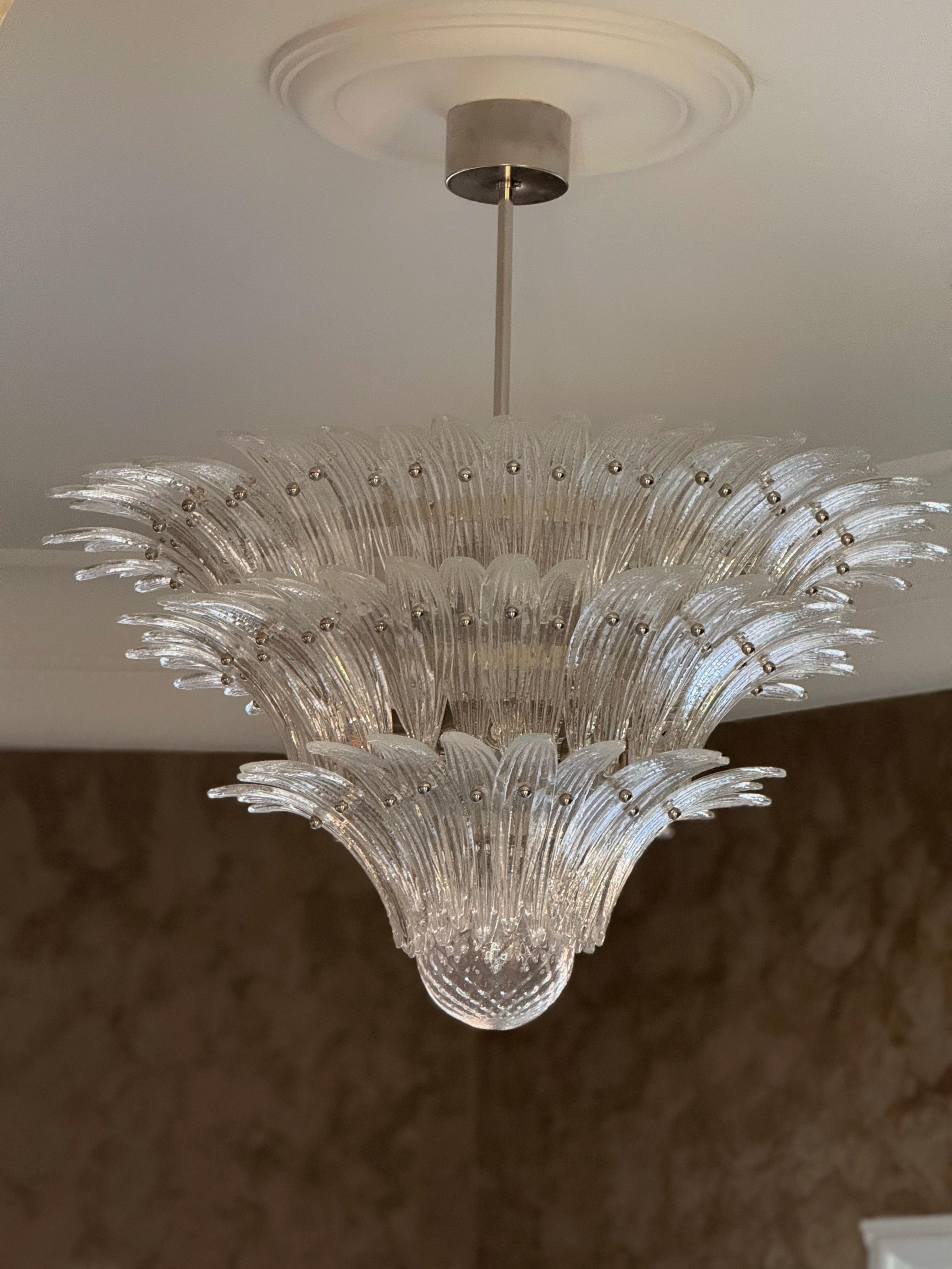 Set of two Bold Eclectic Murano Chandeliers in the style of Barovier.
Italian Palmette chandelier in 1970s style with clear Murano glass leaves arranged in three tiers and mounted on a lamp structure and ceiling rose in chrome. 

Chandelier in