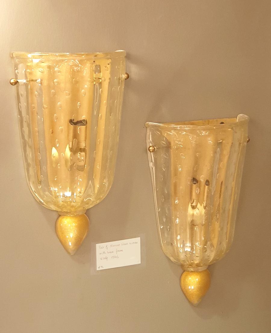 Pair of neoclassical style, Mid-Century Modern Murano glass sconces, attributed to Angelo Barovier, Italy 1960s
The vintage pair is made of thick transparent Murano glass, with gold leaf inclusions.
Frame in brass, 1 candelabra base light, rewired.