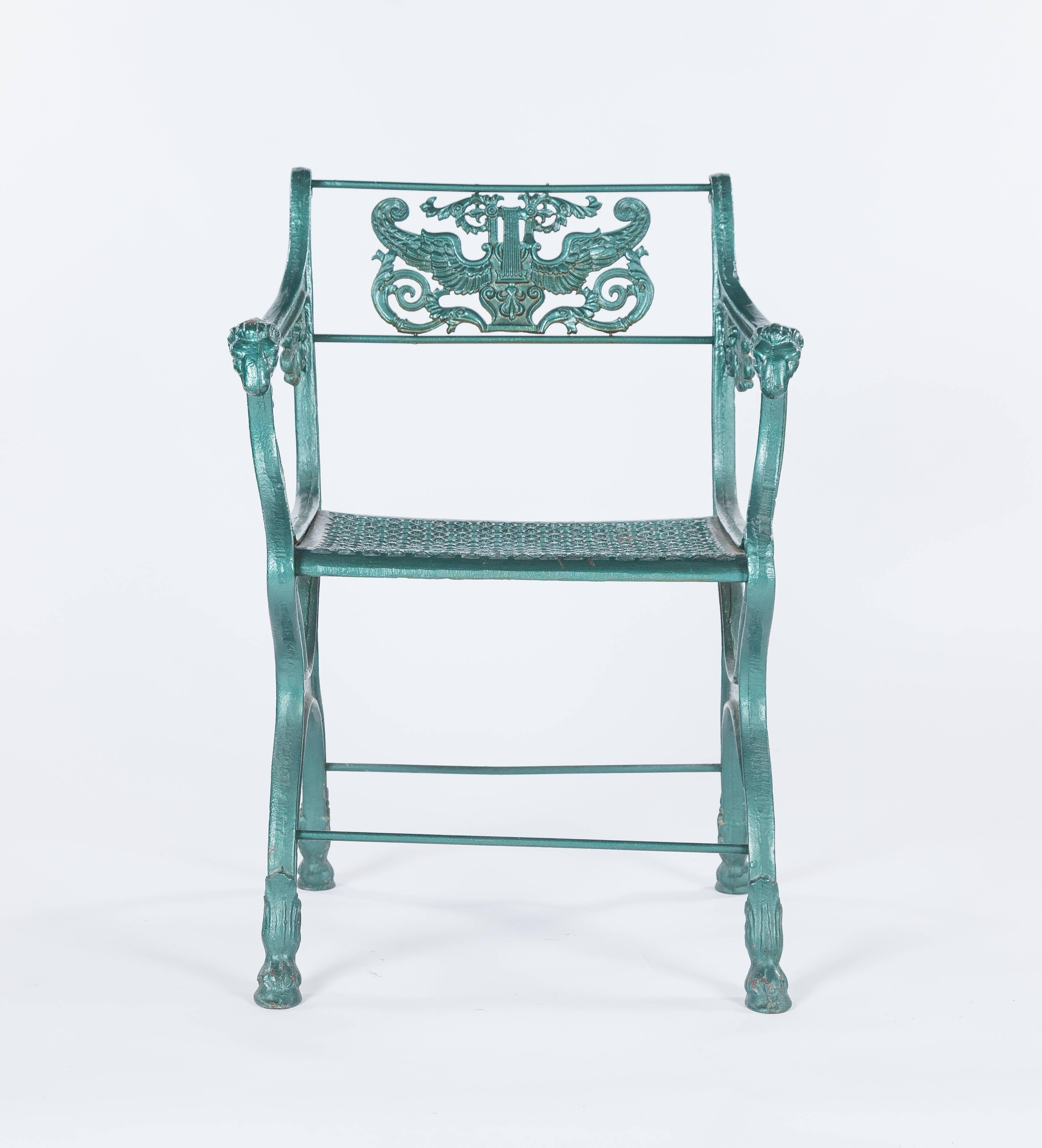A set of two Classic Roman-style English cast iron garden chairs dating to the 19th century. They feature rams head accents on the arms. Each chairs measures approximately 21.5