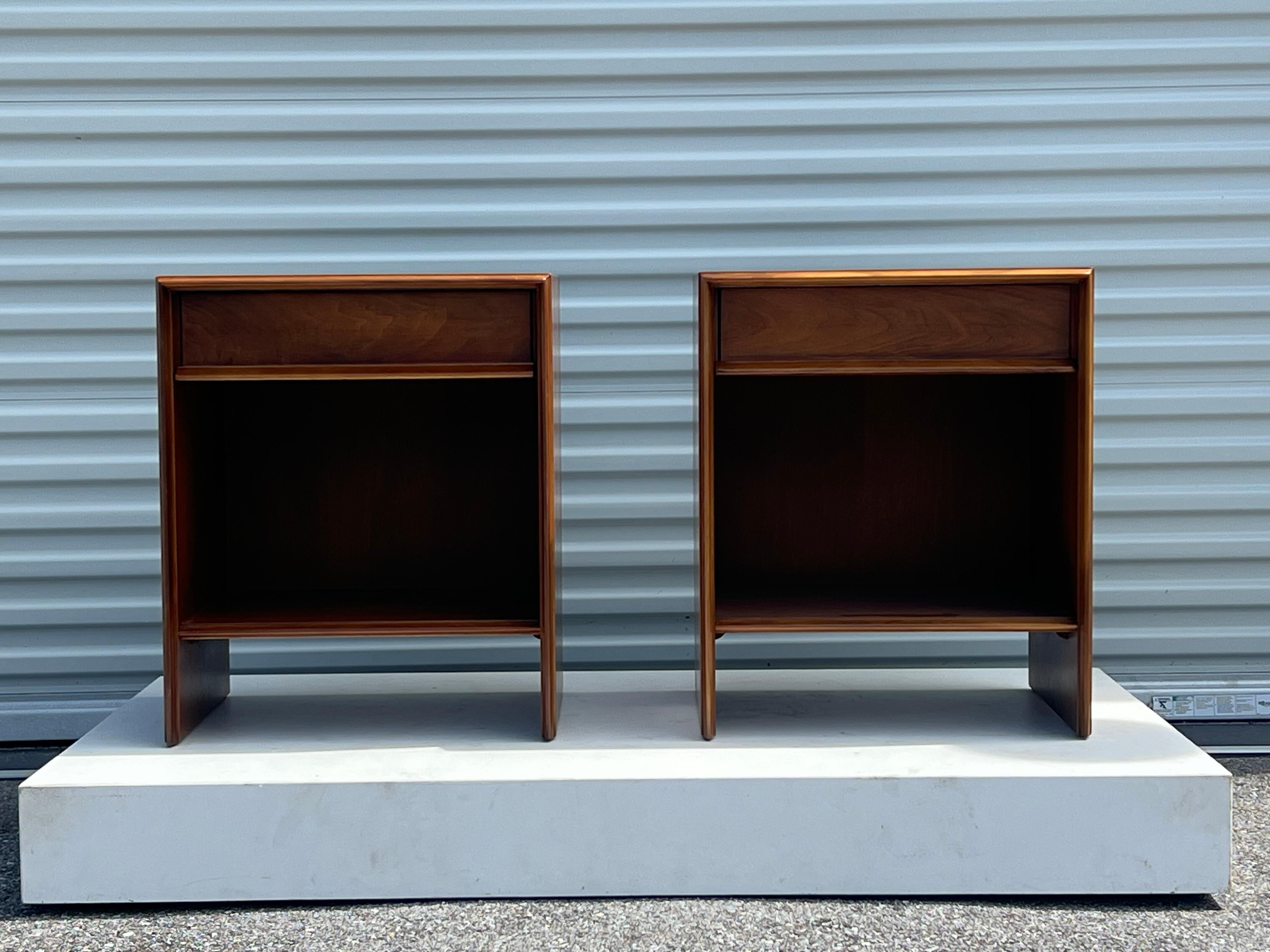A pair of classic boxlike nightstands by T.H. Robsjohn-Gibbings for Widdicomb, circa 1950s. These have a  single recessed top drawer, a lower shelf, and tapered round nose edge detail to the frame. Made of walnut, signed inside each drawer.