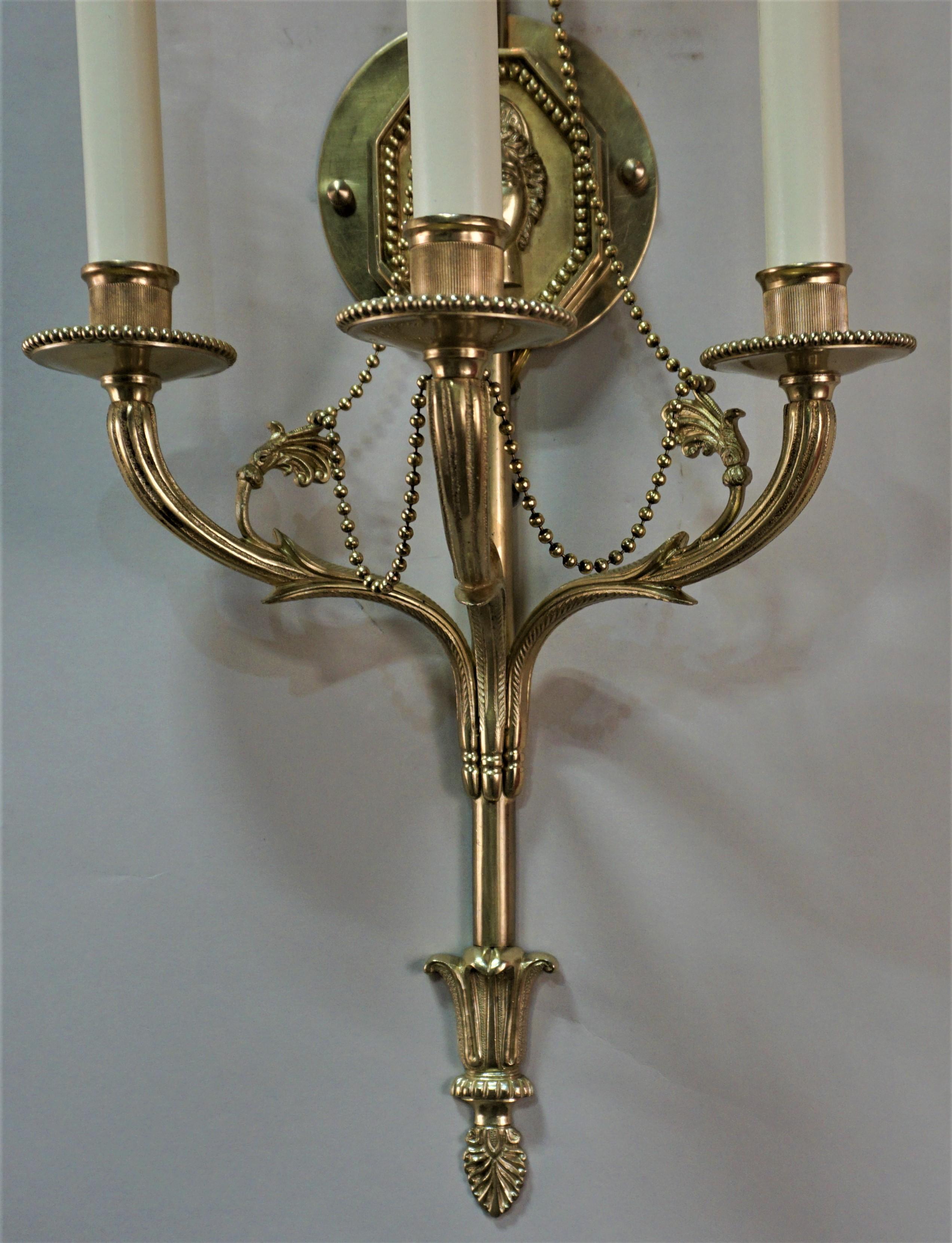 Pair of three-arm bronze wall sconces in classical design.