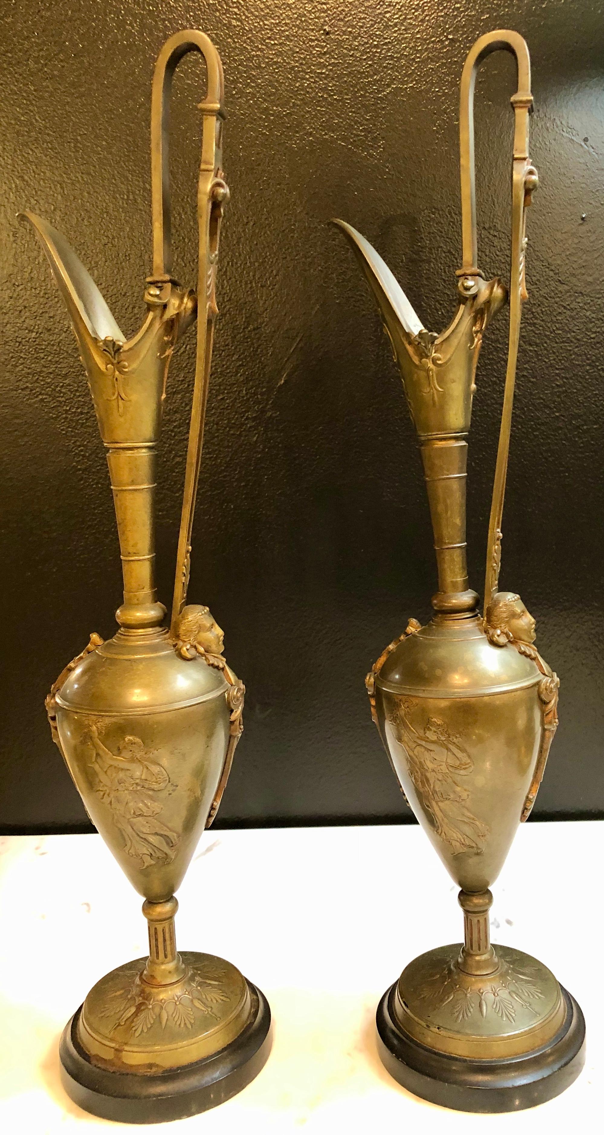 Pair of Classical figurative bronze neoclassical ewers, 19th-early 20th century. Each depicting Grecian woman water bearers along with female torsos having long sleek slender spouts. The pair with handles on marble bases.


LS.