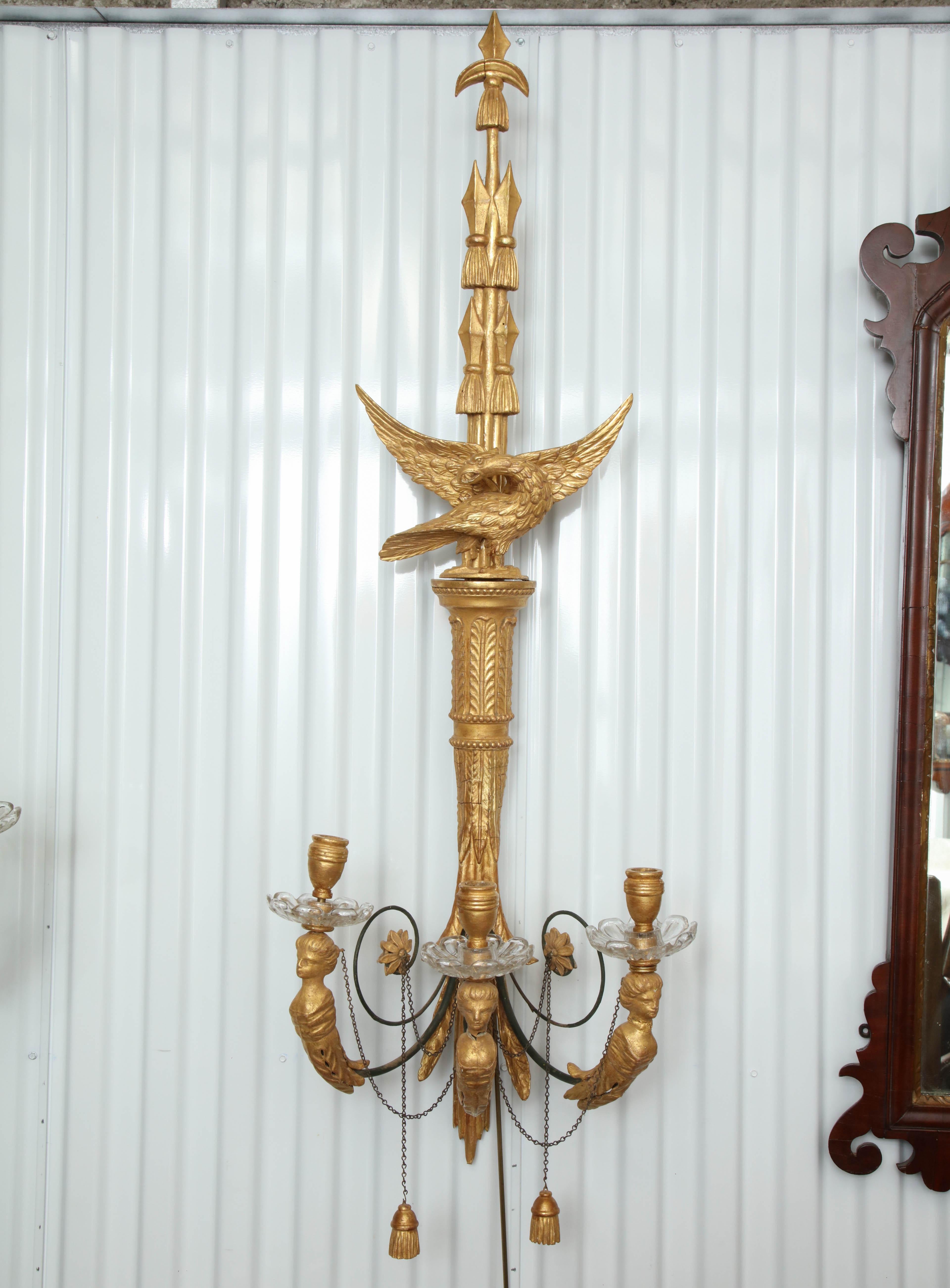 Pair of classical carved eagle giltwood three light wall lights with figural arms, chains and tassels.