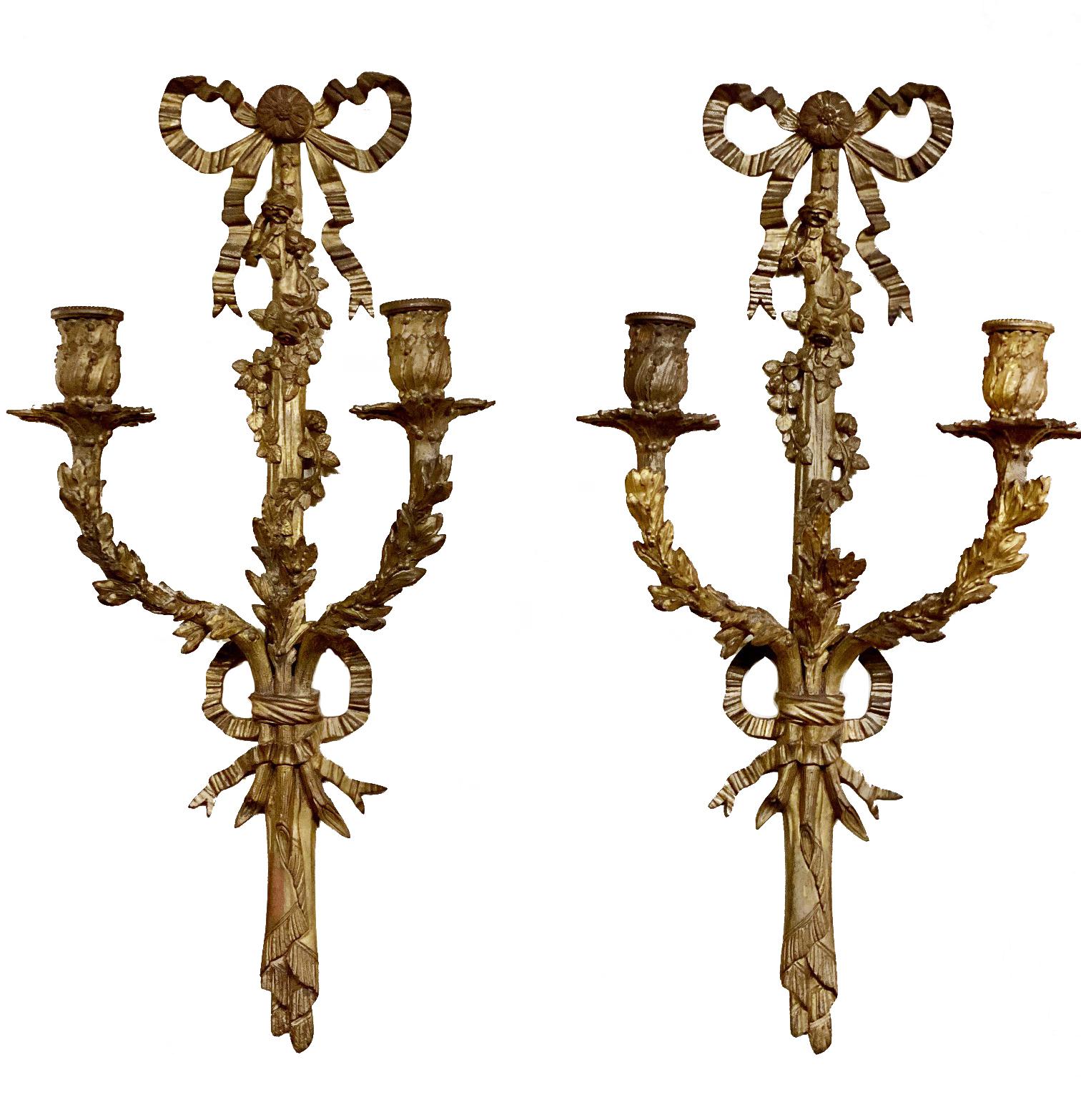 Pair of classical late 19th Century Louis XVI style two branch wall lights each with ribbon and foliate decoration. They have an antique patina which we can wax and retain or have them polished like the previous two pairs.