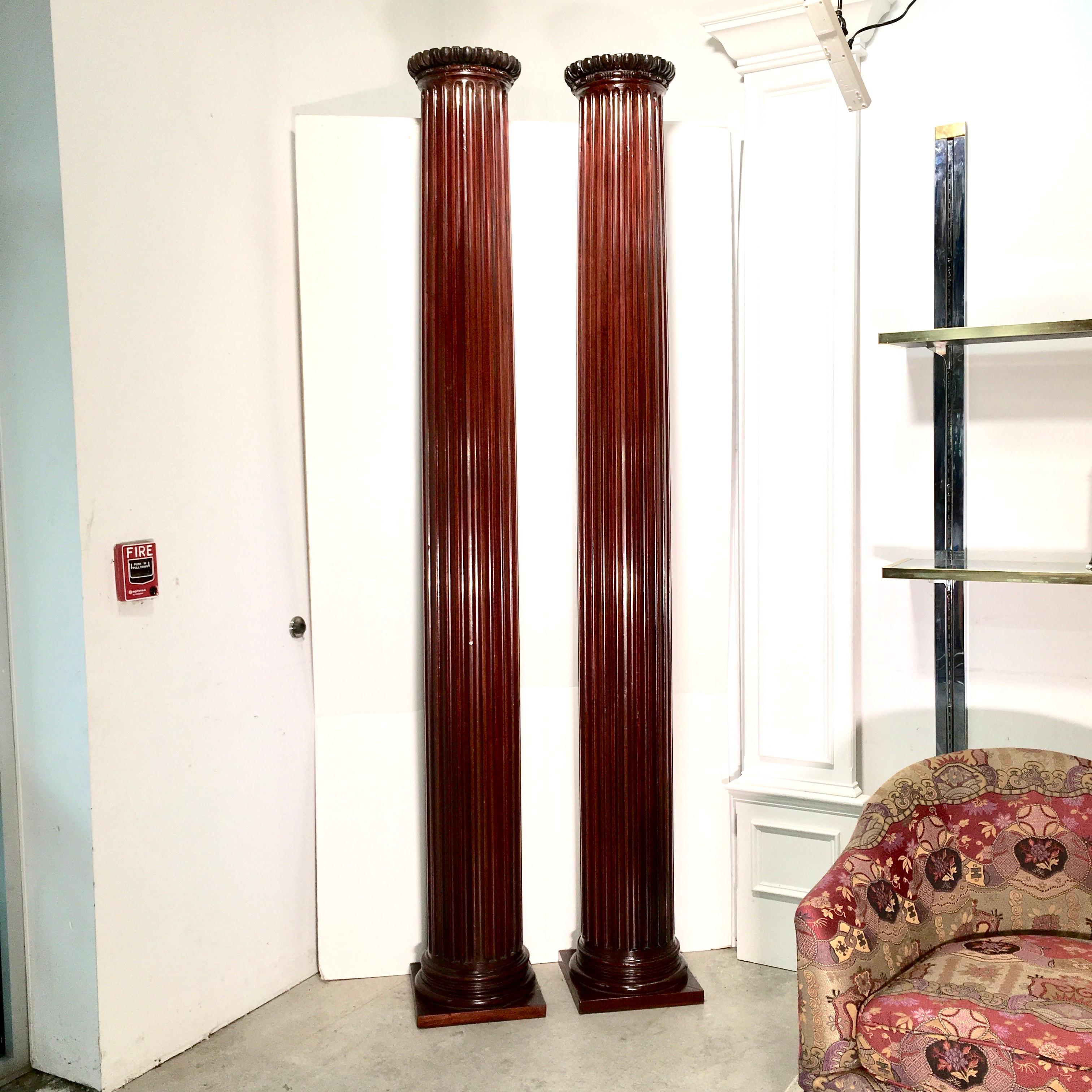 Pair of antique architectural round fluted columns made entirely of solid mahogany, on square base and carved egg and dart capitals. Twenty four flutes as per Vitruvius! Measures: 100 inches tall, 11 inches diameter at entasis, base is 13-5/8 inches