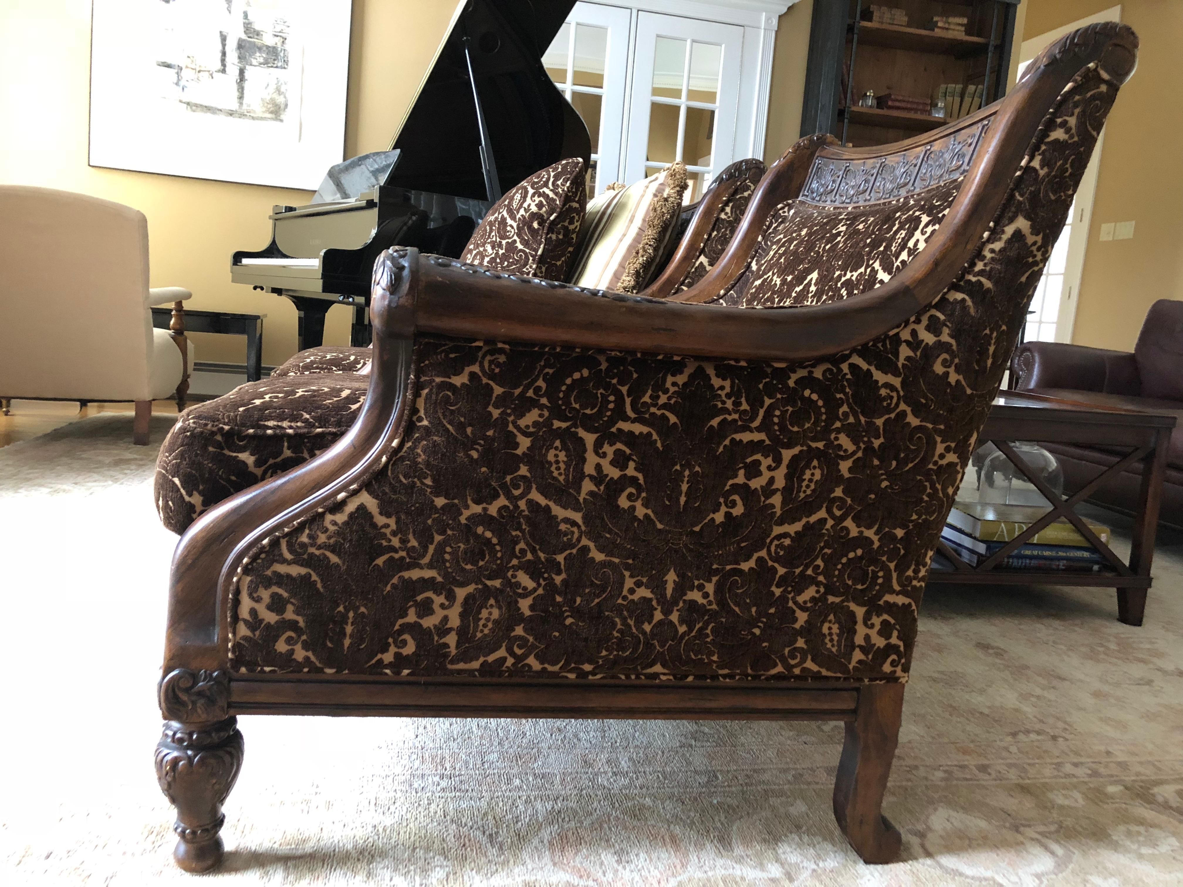 Gorgeous pair of classic carved walnut and richly upholstered Walsh lounge chairs by Century Furniture. The handsome carving appears on arm rests, back header, and feet, and the upholstery is a plush raised velour chocolate brown colored patterned