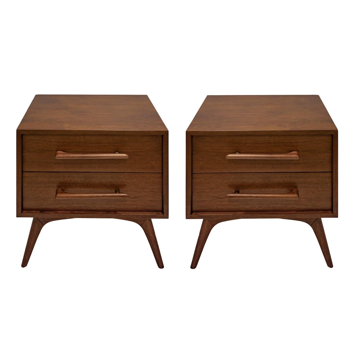 Pair of beautifully tailored bedside tables in walnut with gently splayed legs and elegant handle design with bronze ball elements on each handle, American 1960's. Each has two drawers. The pair have clean lines and are beautiful from every angle. 