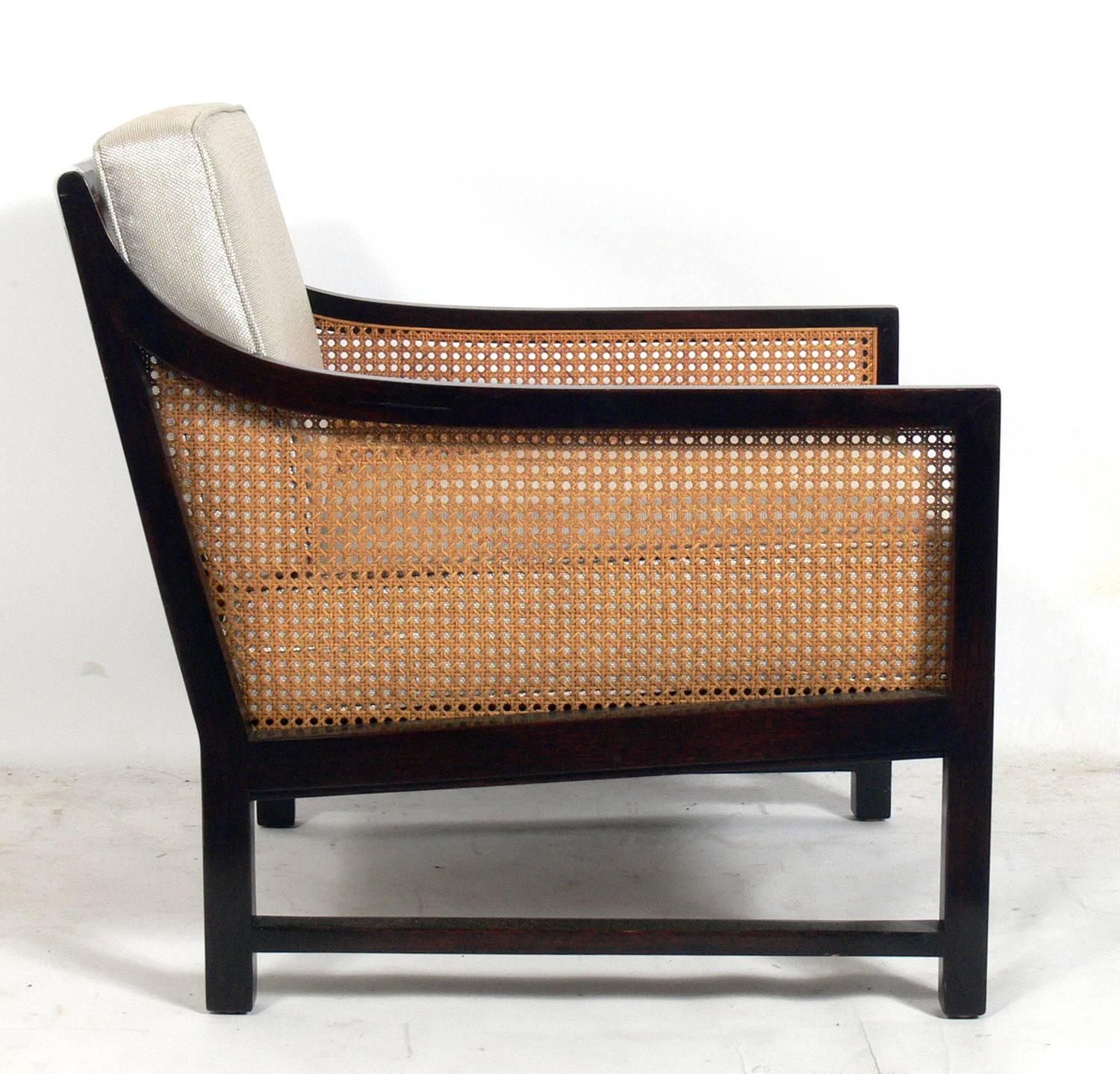 Pair of clean lined caned lounge chairs, American, circa 1980s. They have been reupholstered in an ivory and tan color fabric.