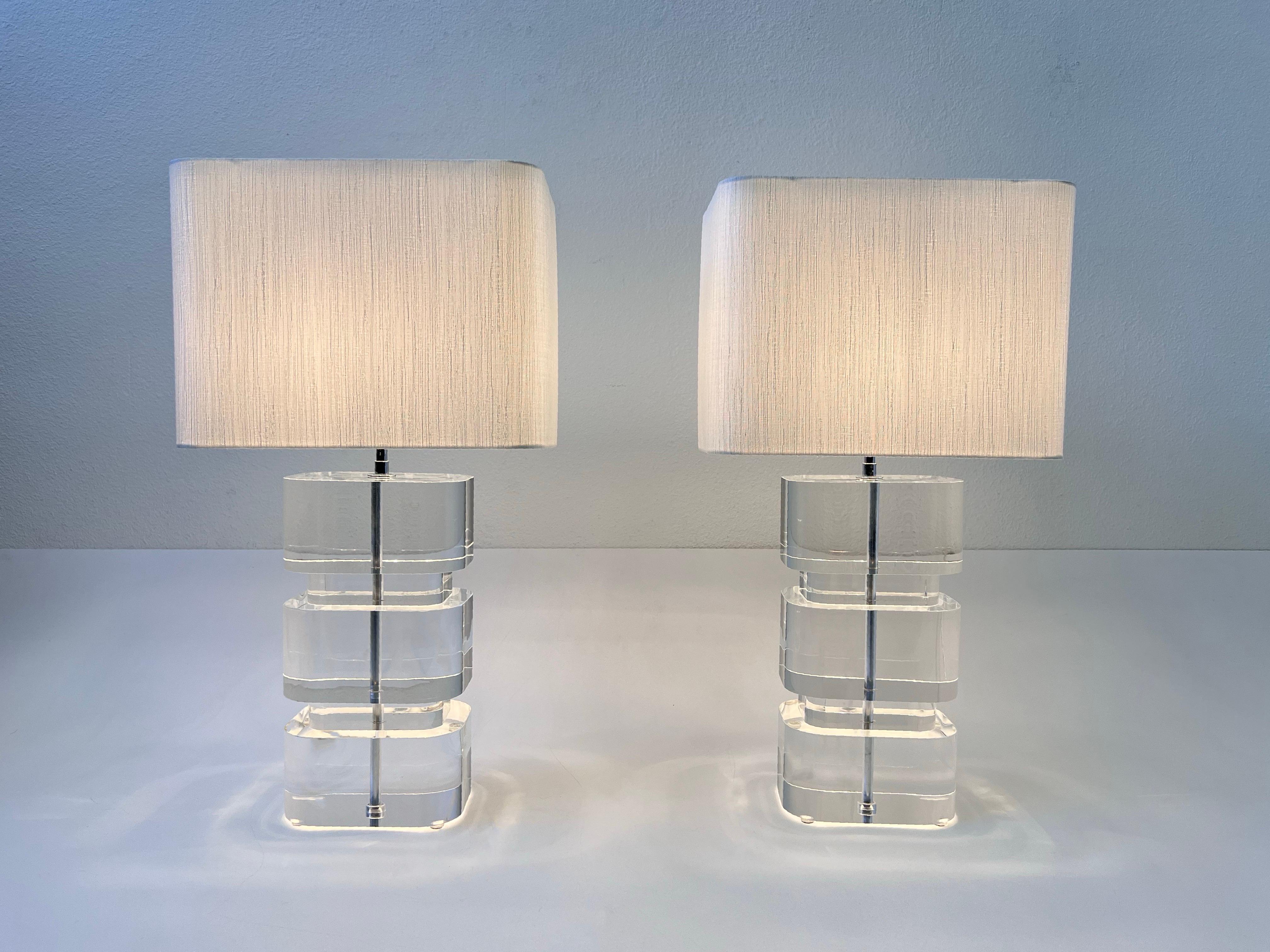 Glamorous pair of clear acrylic and chrome table lamps by renowned designer Karl Springer. 
Newly professionally polish acrylic and rewired with new custom white silk shades. 

The hardware is in original condition it shows minor wear consistent