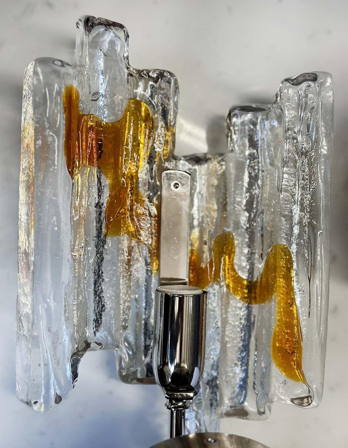 Paire d'appliques vintage en verre de Murano fabriquées en Italie dans les années 1960 et présentant une fusion de teintes claires et ambrées. Le verre transparent permet un jeu d'ombre et de lumière fascinant, créant une ambiance captivante dans