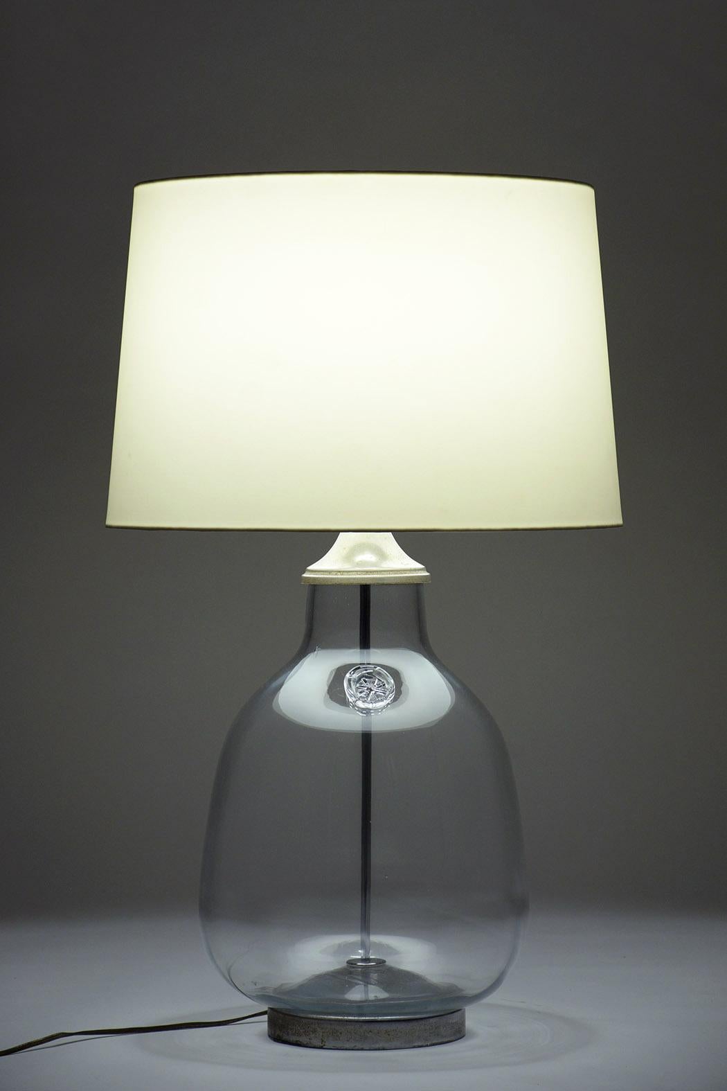 This vintage pair of blown glass lamps are in good condition and they come with a clear glass bottle shape vase and this pair comes with a stamped in the center. The lamps feature an 11-inch harp topped with round brass finials, round chrome bases,