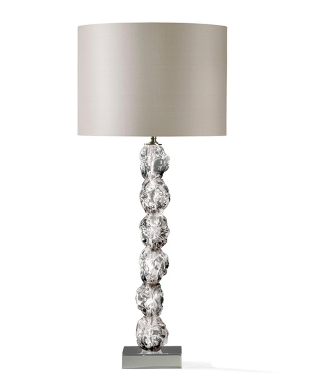 This is a very glamourous table lamp, for its dimensions and for the crystal glass details made as raw pieces, that are very surprising and charming. The raw crystal glass is put in contrast with the elgance of the silk lampshade; the pair it is a