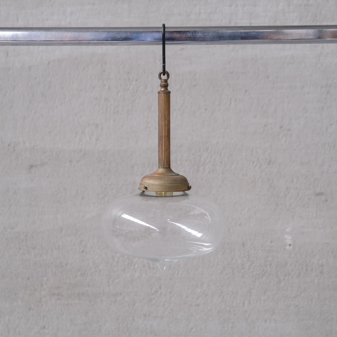 A pair of good quality brass and glass pendant lights.

France, c1950s.

Tall brass gallery, with clear glass tear drop shaped shade.

Price is for the pair.

No chain or rose was retained, however they are easy to source online.

Good vintage