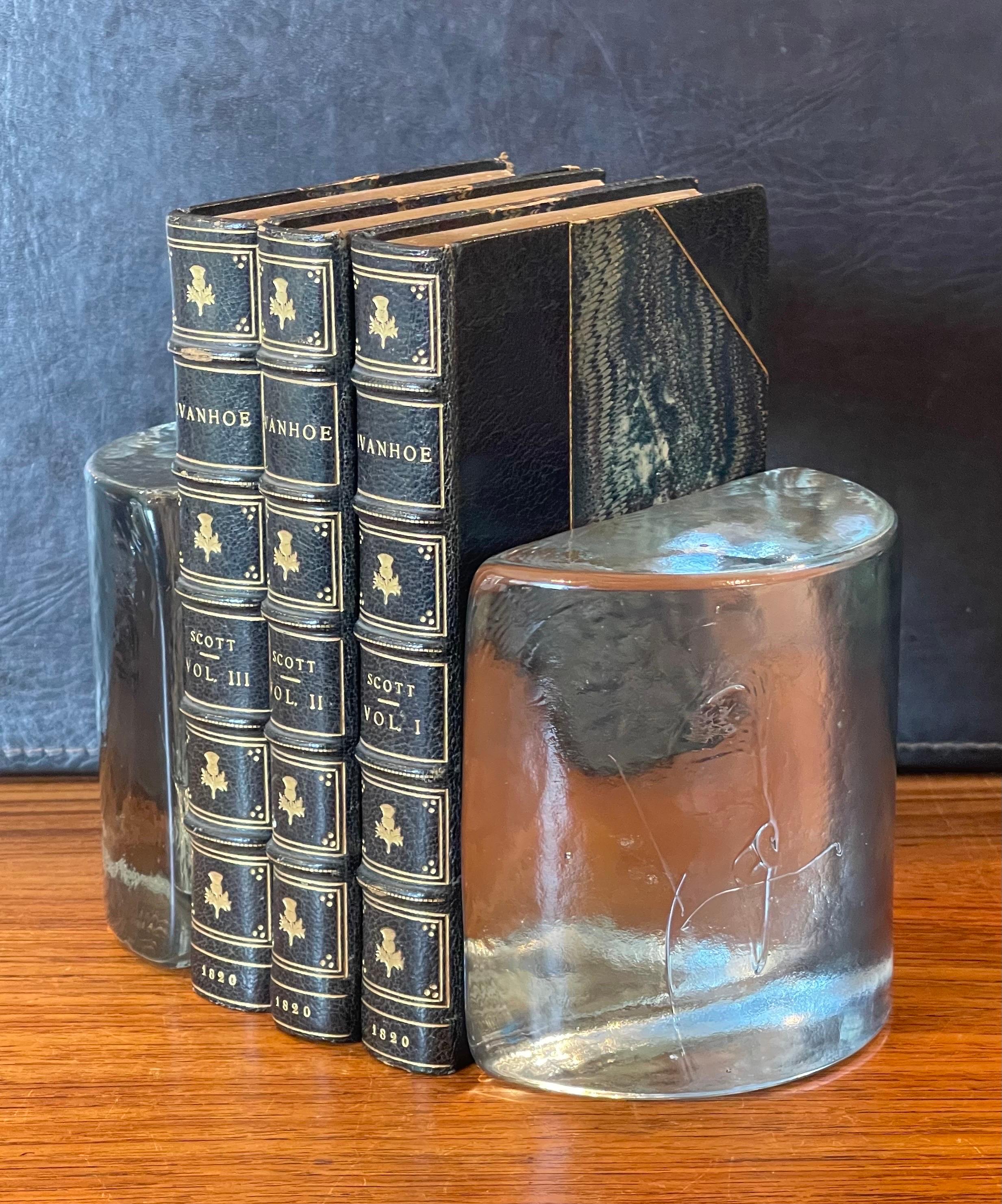 Gorgeous clear glass half moon bookends designed by Wayne Husted for Blenko, circa 1960s. They are in very good vintage condition with no chips or scratches.   The pair are 5