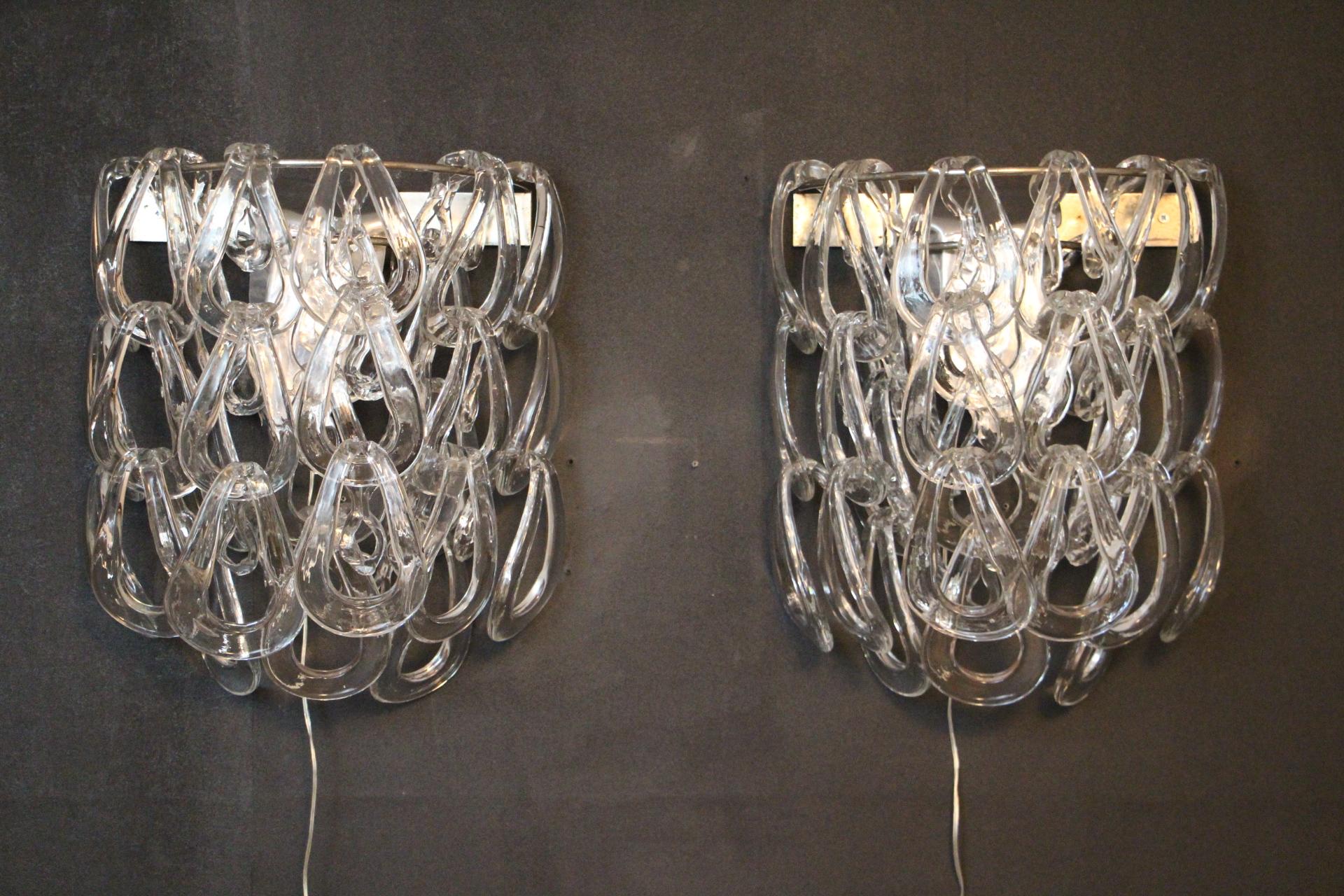 Dieses schöne Paar Wandleuchten von Angelo Mangiarotti für Vistosi besteht aus einer Reihe von miteinander verbundenen eiförmigen Schirmen aus durchscheinendem Murano-Glas, die auf einem Chromgestell befestigt sind. Jedes Glasteil haftet an dem