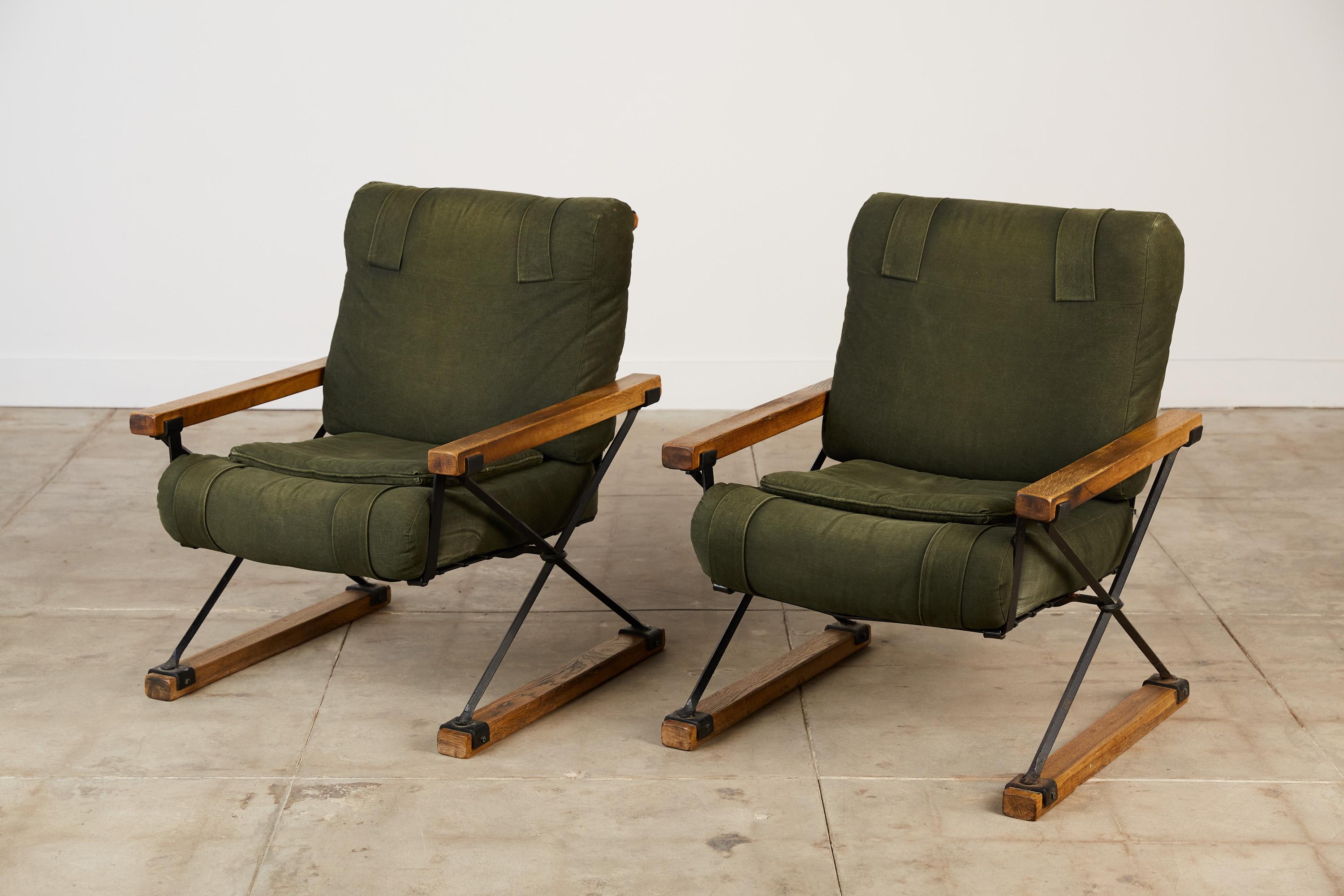 A pair of Cleo Baldon lounge chairs for Terra, USA, c.1960s. The chairs feature a wrought iron base with x-frame profiles. They're grounded by rectangular blocks as the legs with the same design element mirrored in the armrests. The pair still