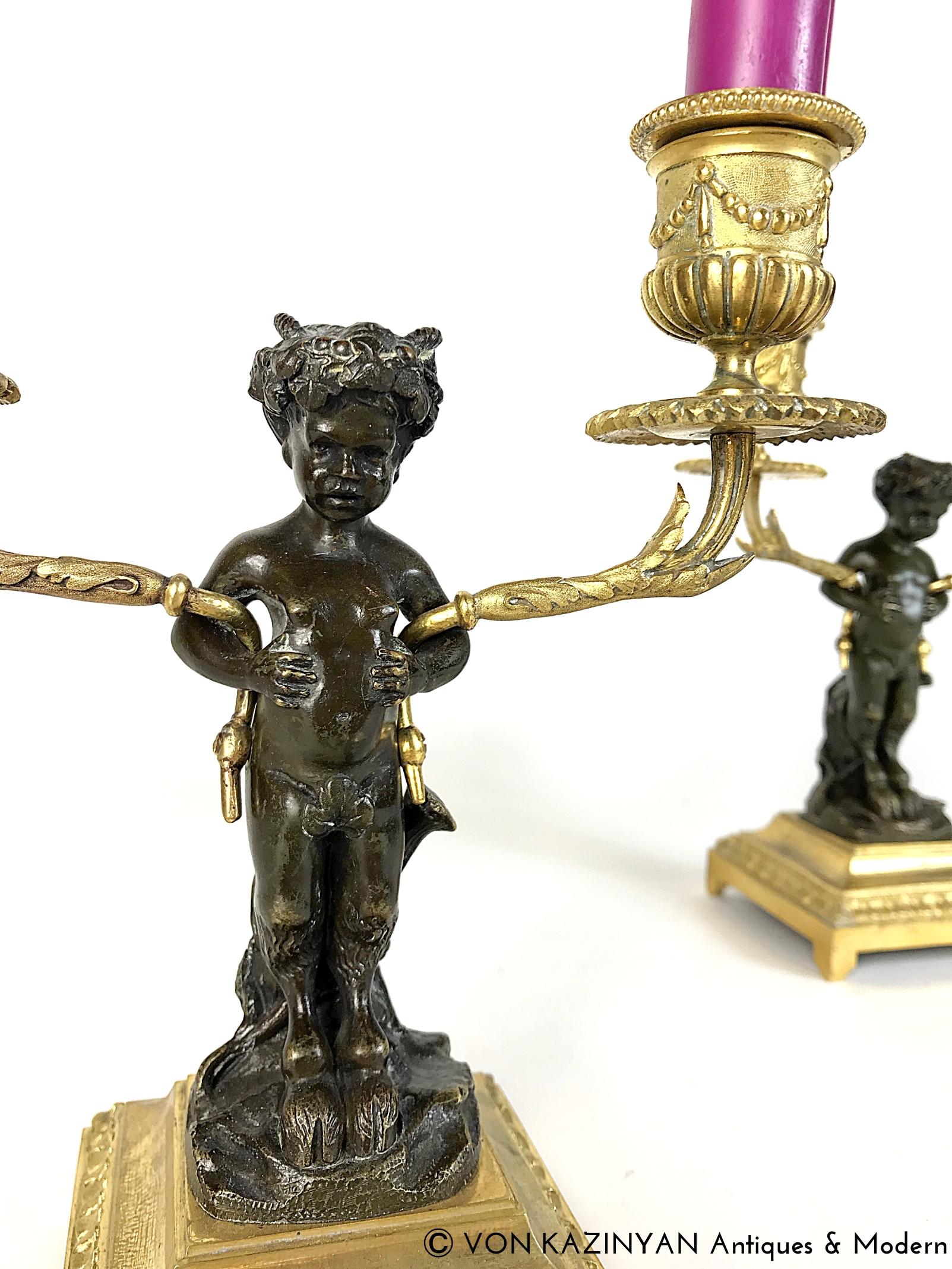 Una coppia di meravigliosi candelabri francesi in bronzo dorato e patinato realizzati da Atelier A Clodion a metà del XIX secolo. Raffigura due satiri in bronzo patinato seduti su un ceppo d'albero che tengono in mano due rami con bacche dorate che