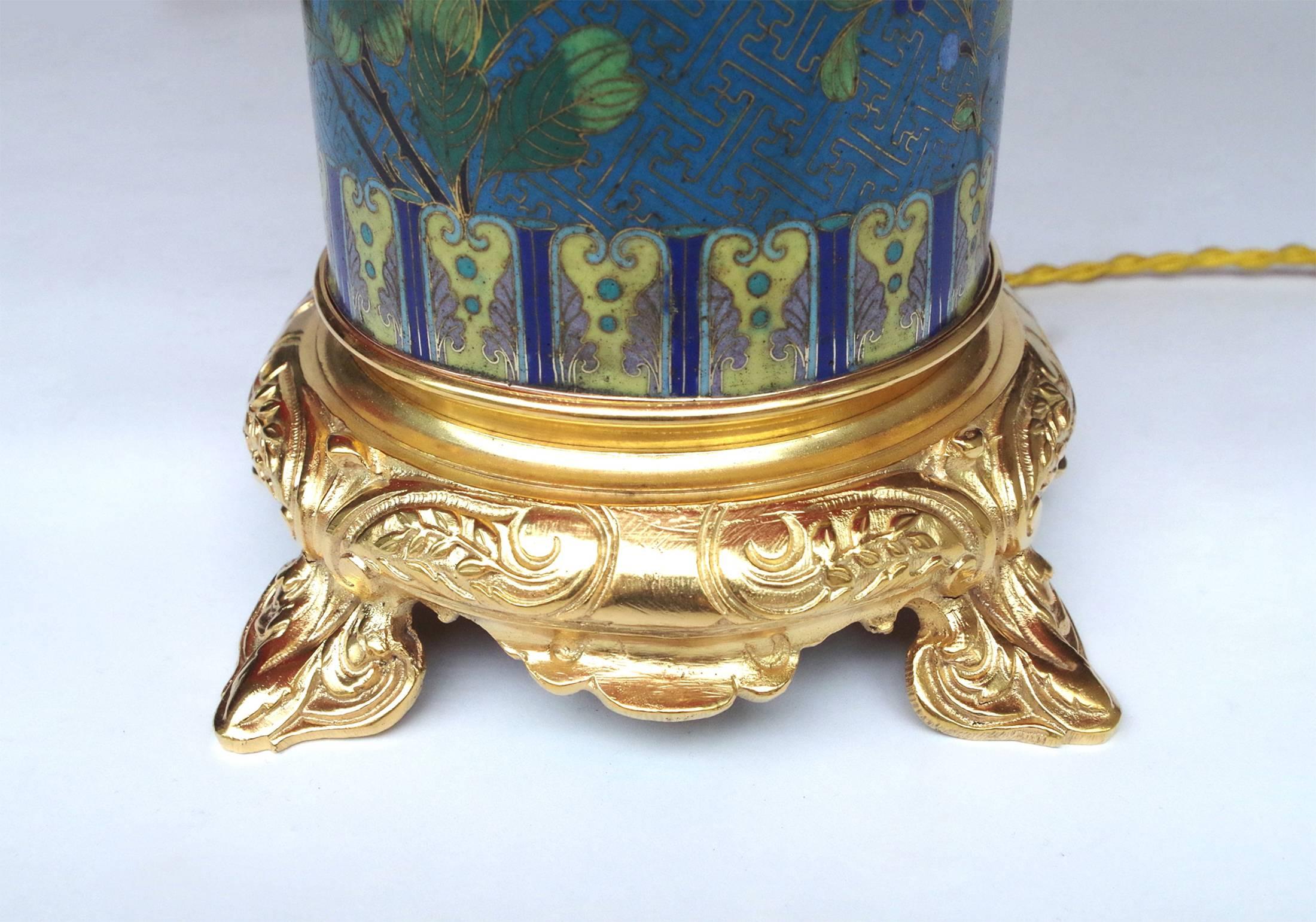 Pair of cloisonné enamel Japanese style roll shaped lamps with a gilt bronze mounting.
Blue turquoise enamel background with Buddhist swastika and decoration of polychrome
flowered cherry branches framed by friezes of Ru-Yi clouds. Round gilt bronze