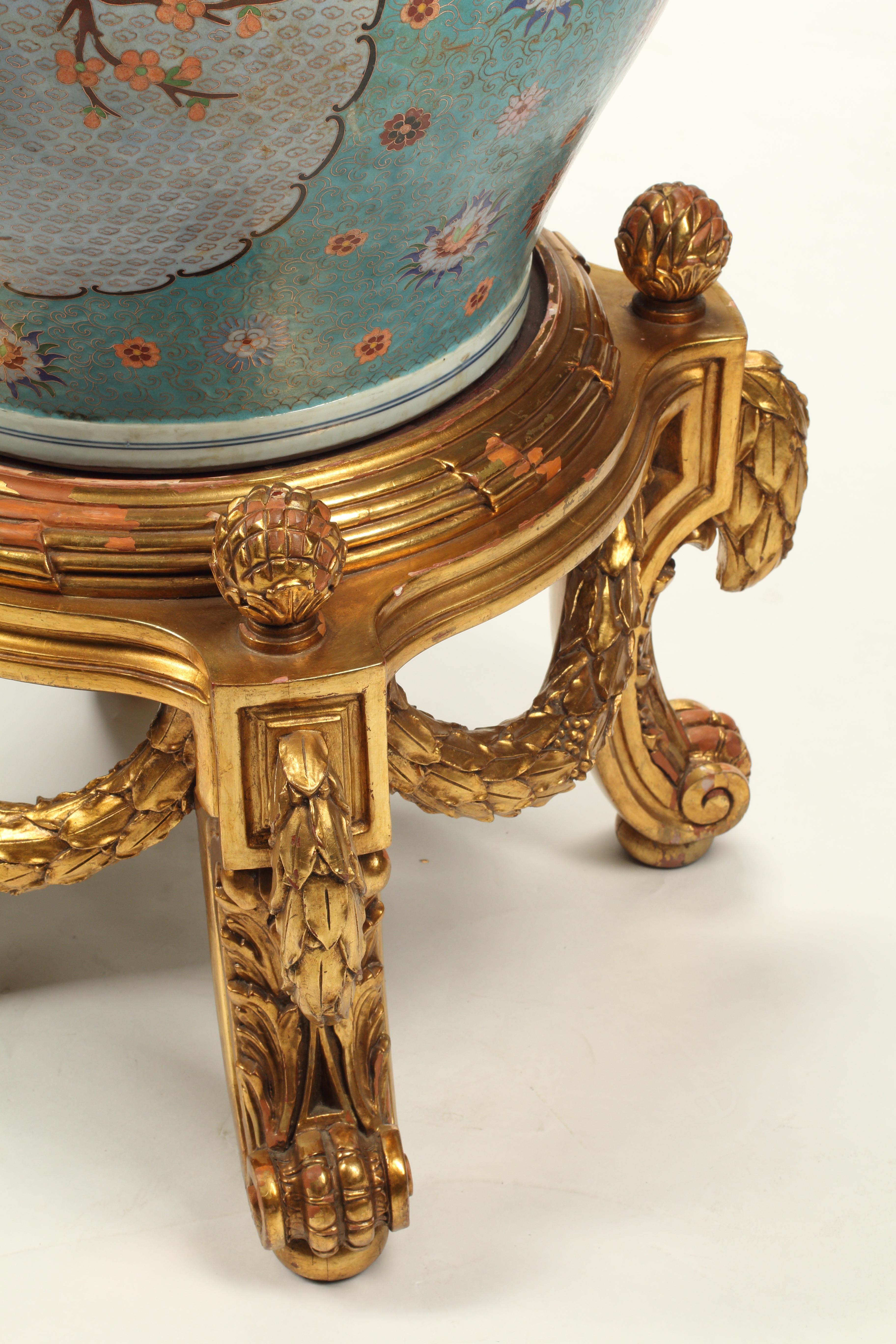 Una coppia di grandi vasi cinesi del XX secolo che rappresentano uno splendido esempio di cloisonné su porcellana. Uno sfondo prevalentemente turchese con accenti floreali è presente in tutto il locale e circonda grandi centrotavola raffiguranti