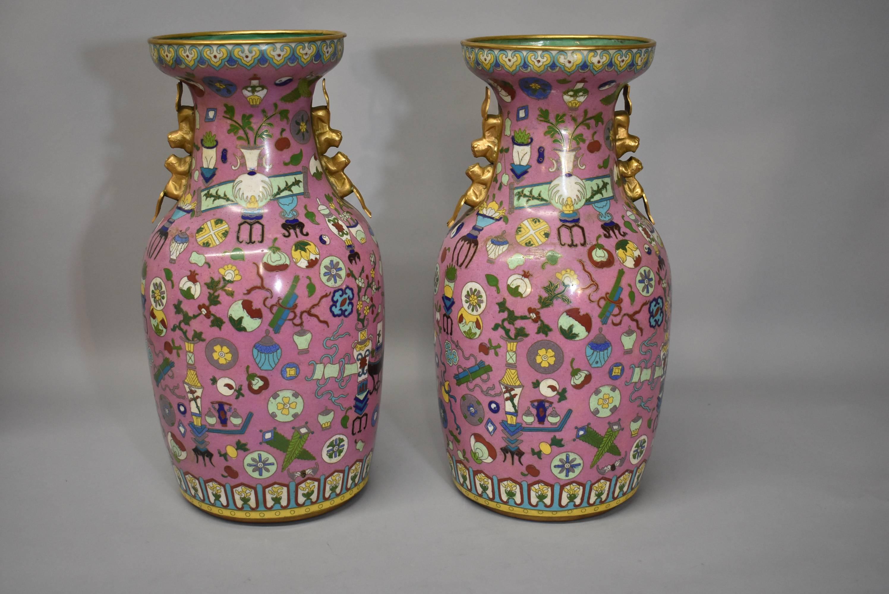 A beautiful pair of cloisonné vases in the Hundred Treasures pattern. This stunning vases feature a rose tone with applied brass handles with a double squirrel design and a decorated bottom. Very good condition with two old repair as photoed. The