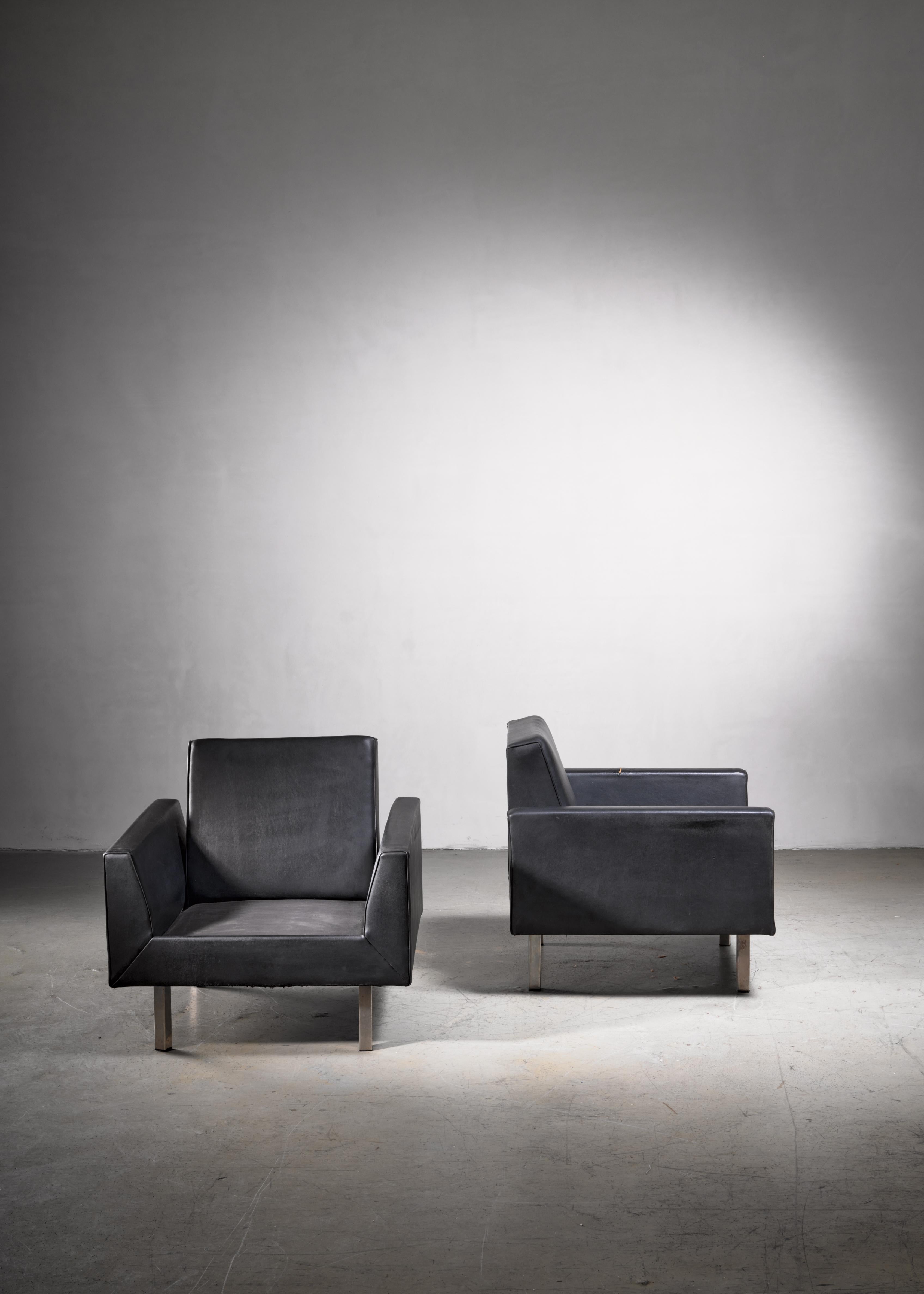 A pair of early model 410 club chairs by Dutch designer Theo Ruth for Artifort, 1950s. The chairs are upholstered in the original black Artifort leatherette and have metal legs.