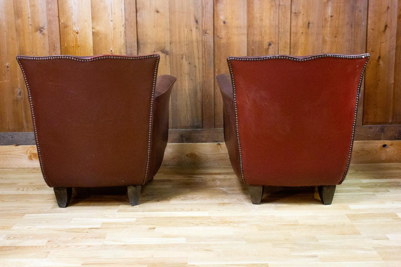 Pair of beautiful club chairs in patinated leather from the art deco period 1940. Known to be large and very comfortable, these are iconic chairs. Slight differences in leather are visible due to old restoration.