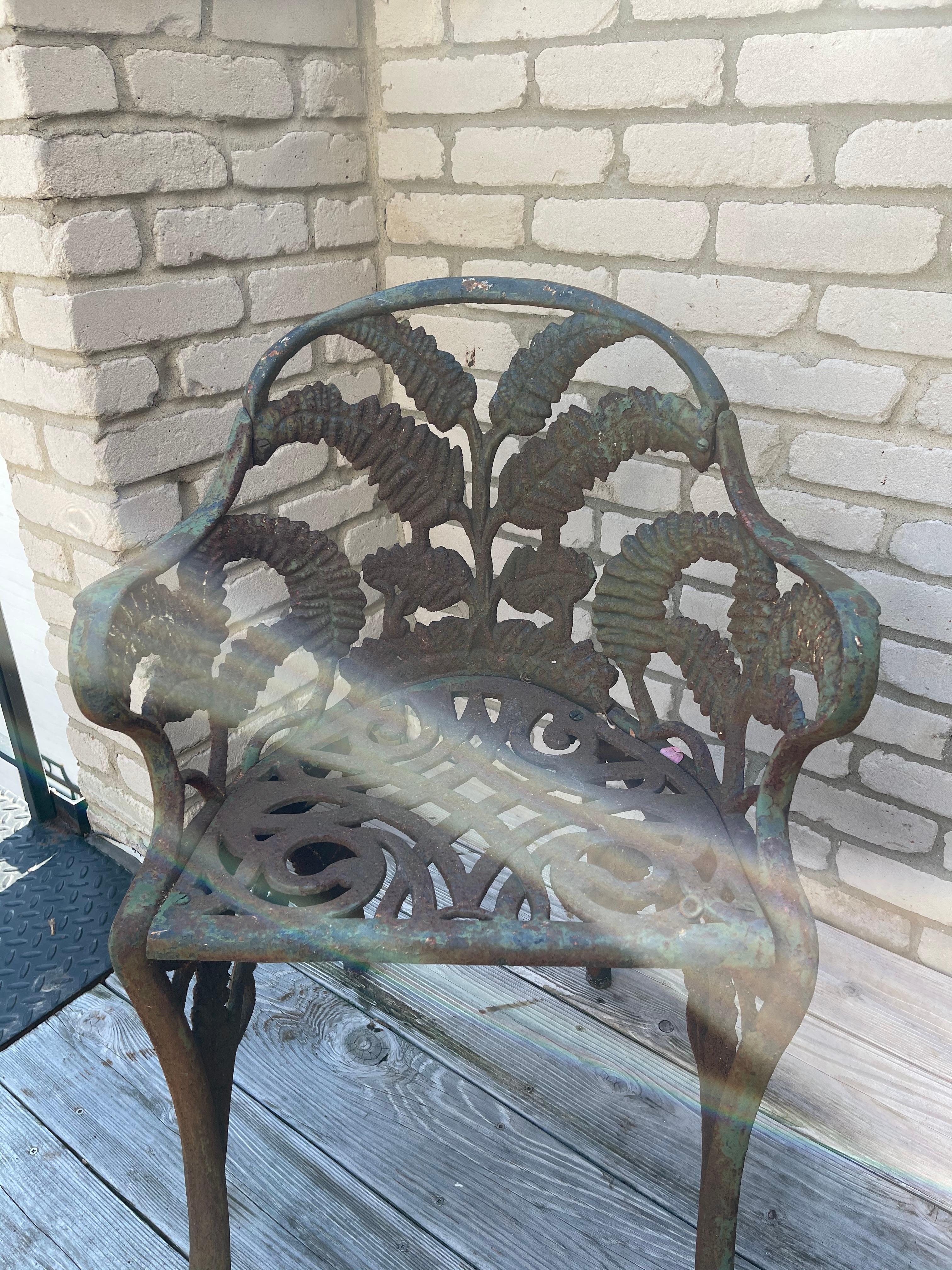 Naturalistic painted green heavy cast iron garden chairs in the style of Coalbrookdale Iron Foundary. The well-defined rounded back splat and arms with uniquitous fern and clusters of blackberry motif. Comfortable and shapely iron pierced scrolled