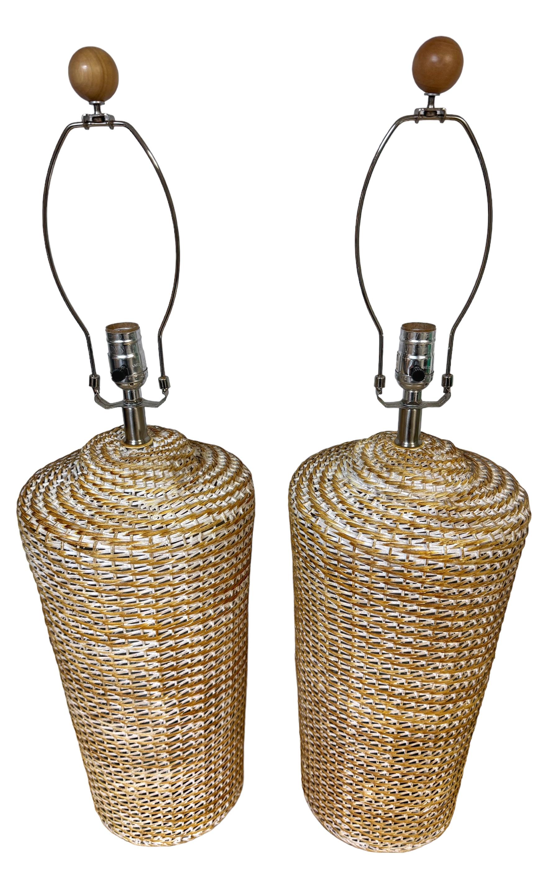 Pair of Coastal Modern White-Polychromed Woven Rattan Lamps 
USA, circa 1980s

A striking pair of coastal modern white-polychromed woven rattan lamps originating from the USA circa the 1980s. These organic lamps are of large scale and feature subtle
