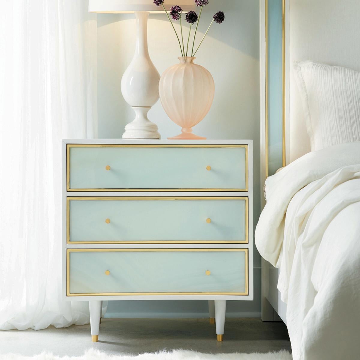 Coastal Sea Glass Nightstand. With a white lacquer case and sea glass foam acrylic drawer fronts, the three drawers are framed with brass surrounds and have modern brass knobs, with soft closing drawers and raised on turned and tapered