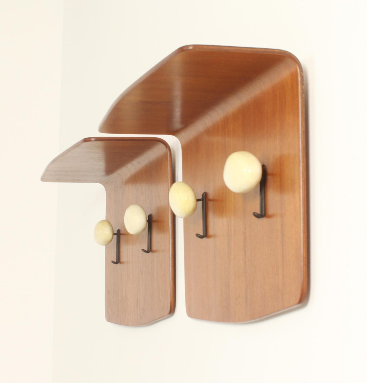 Pair of wall-mounted coat racks designed in 1950's by Franco Campo and Carlo Graffi for Home, Italy. Curved teak wood and two metal and ceramic coat hooks by the Italian ceramist Victor Cerrato. Signed with Home label. 