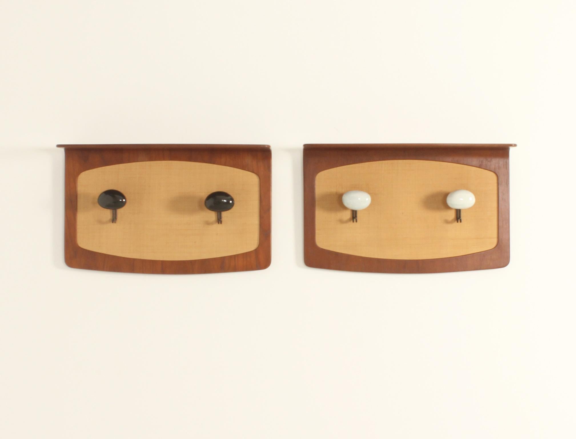 Pair of wall-mounted coat racks designed in 1950's by Franco Campo and Carlo Graffi for Home, Italy. Curved teak wood with seagrass front panels and two metal and ceramic coat hooks by the Italian ceramist Victor Cerrato. 