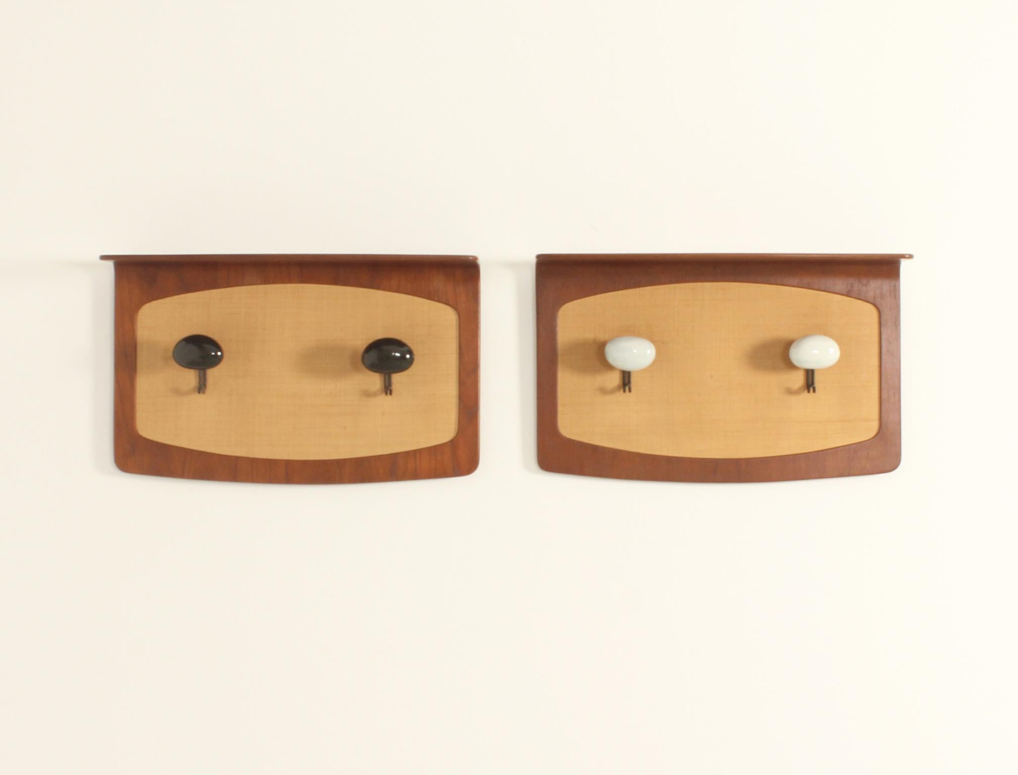 Paire de porte-manteaux muraux conçus dans les années 1950 par Franco Campo et Carlo Graffi pour Home, Italie. Bois de teck courbé avec façades en gazon de mer et deux patères en métal et céramique du céramiste italien Victor Cerrato. 